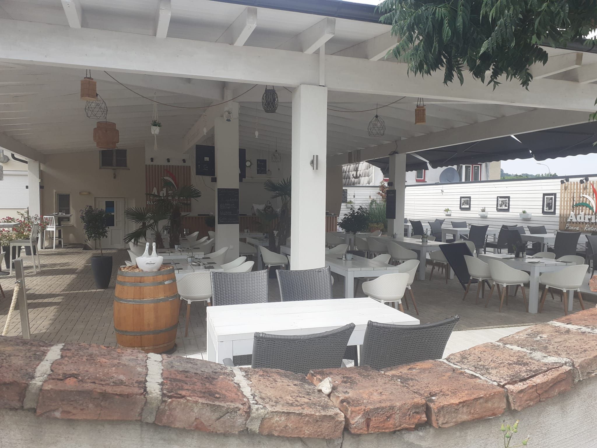 A covered guest garden with white tables and chairs, surrounded by plants and decorations.