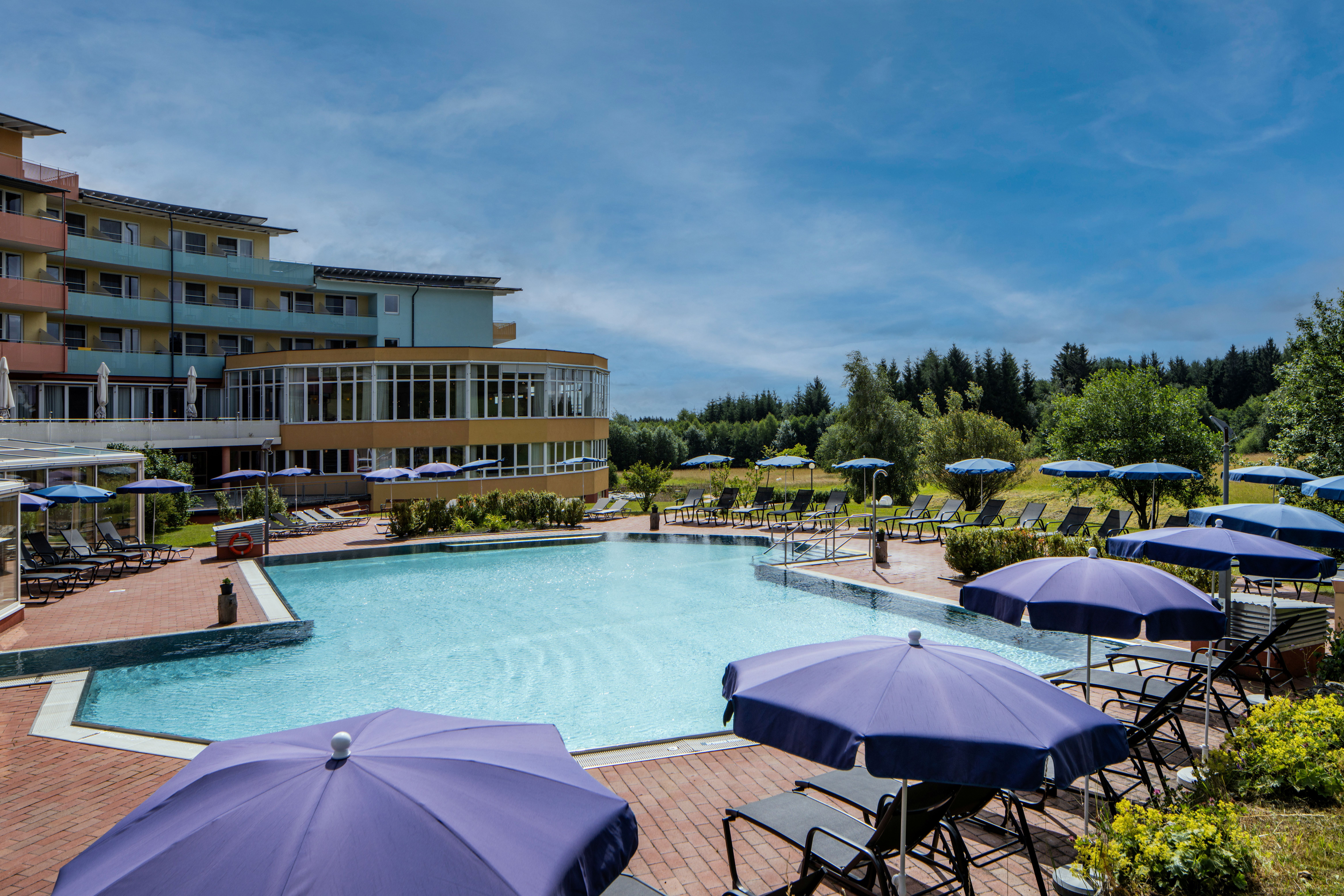 Exterior view of a hotel with a pool and umbrellas.