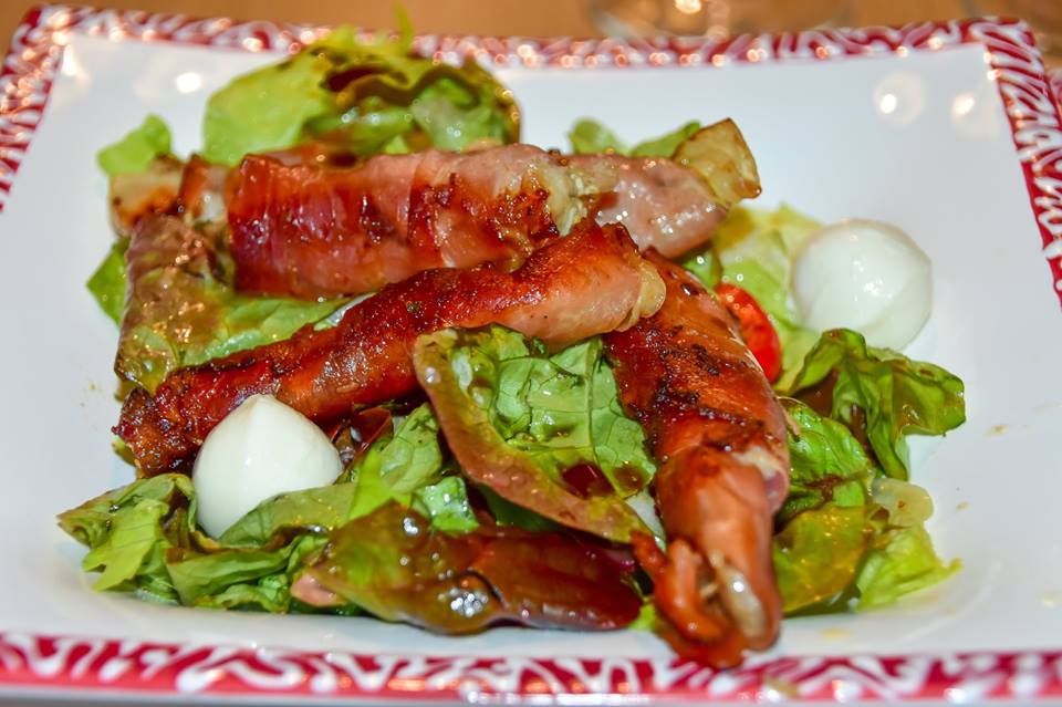 Dish with carp wrapped in ham on a leaf salad.