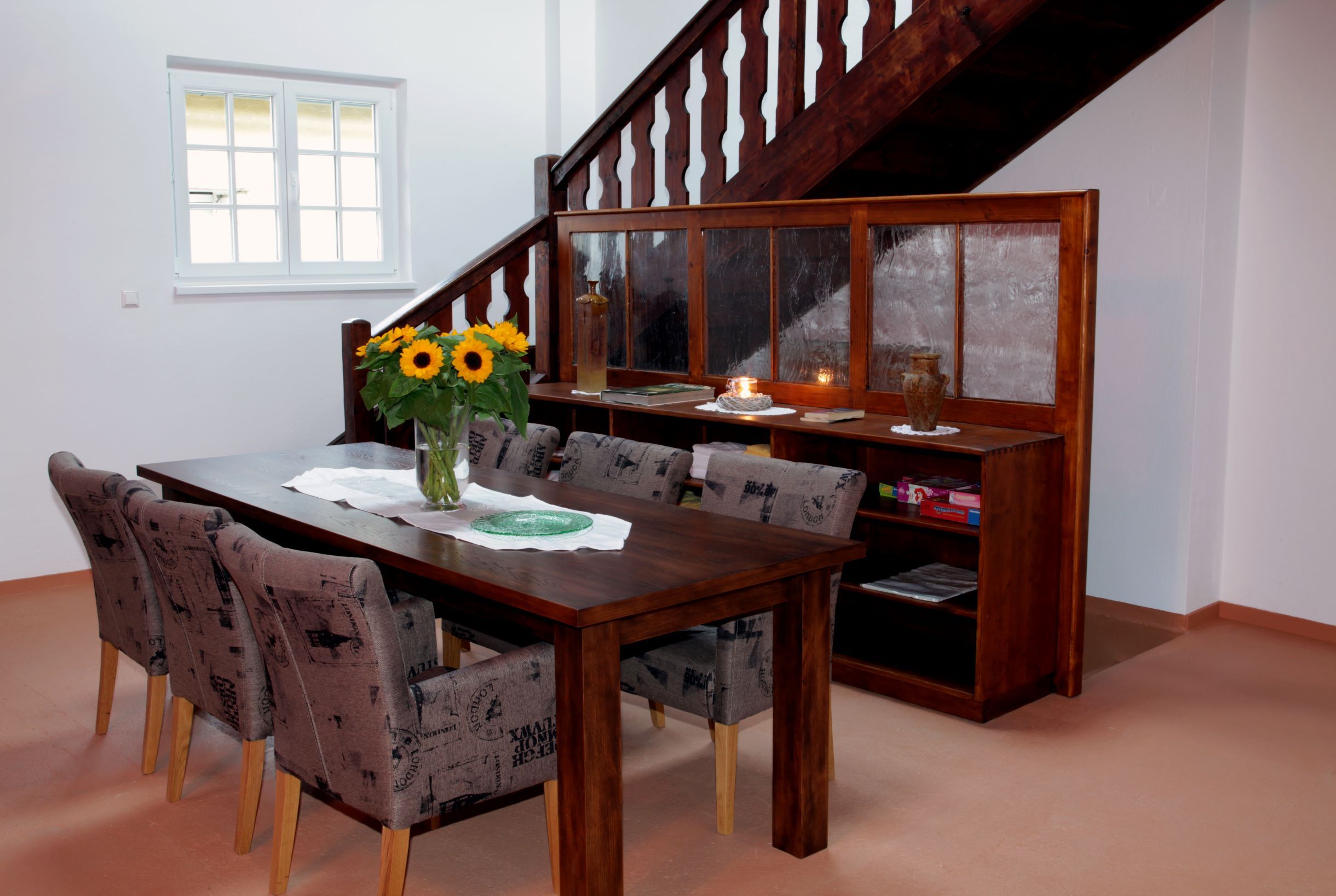 Dining area with wooden table, chairs and sunflowers in a loft.
