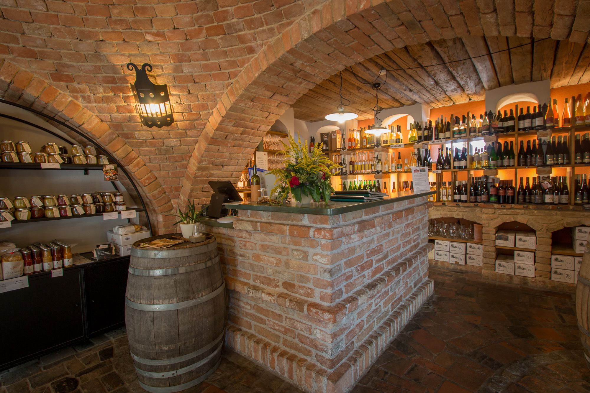 Cozy wine bar with brick walls, shelves full of wine bottles and a rustic counter.