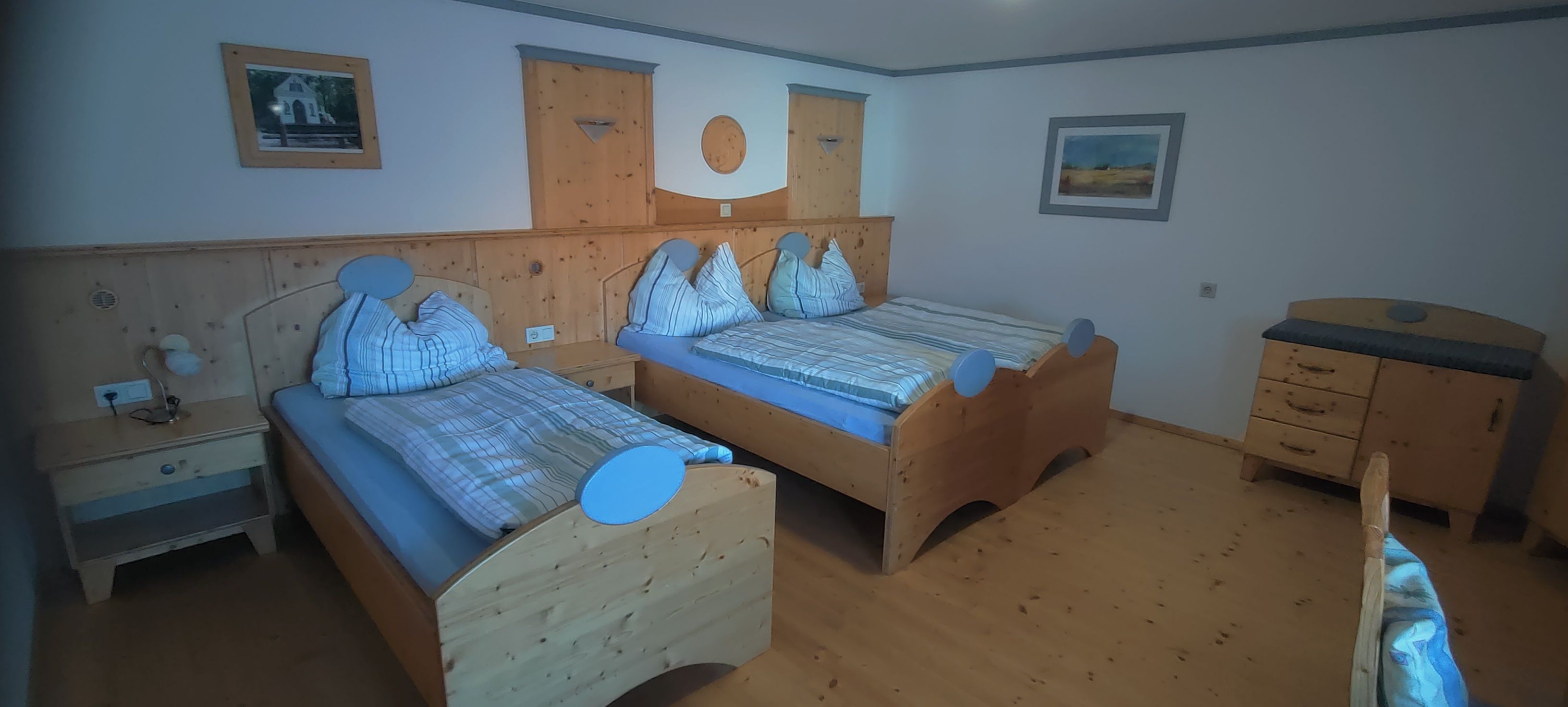 Comfortable bedroom with two single beds made of wood, bedside table and chest of drawers.