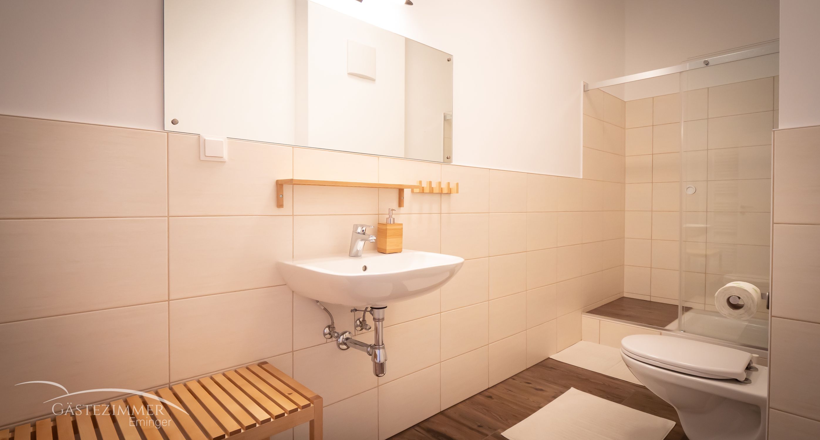 Modern bathroom with washbasin, mirror, shower and toilet.