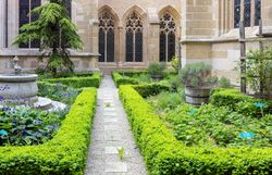 Top Ausflugsziel Stift Klosterneuburg, Innenhof mit gepflegten Hecken, Blumen, Kräutern, einem kleinen Brunnen und einem Baum.