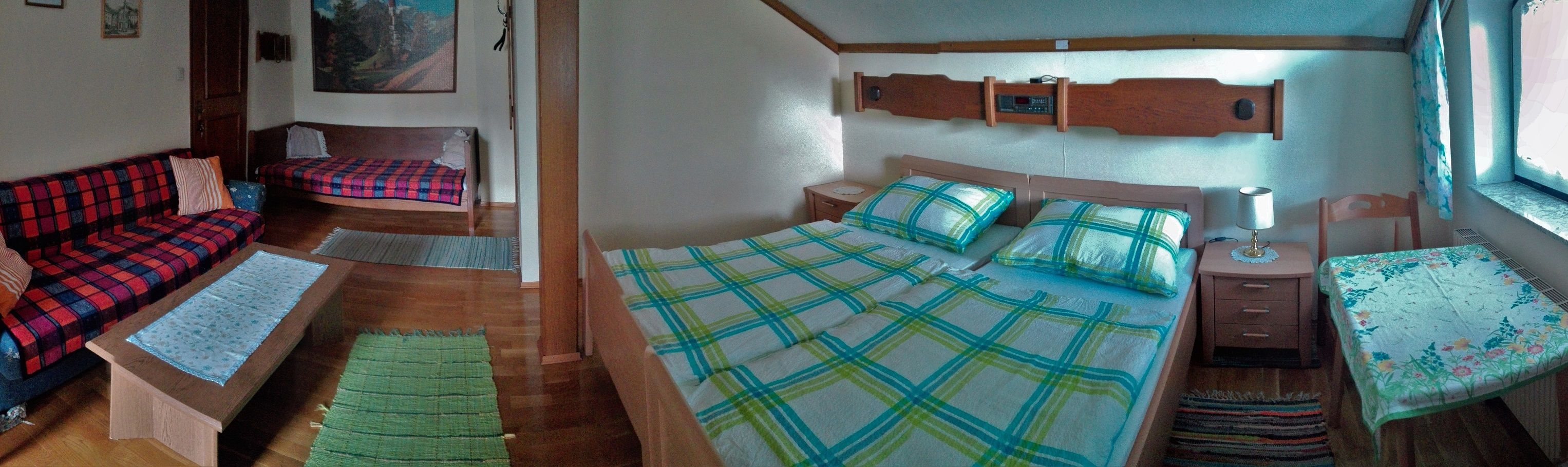 A cozy room with double bed, sofa, table and window.