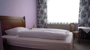 A simply furnished hotel room with a bed, table and chair.