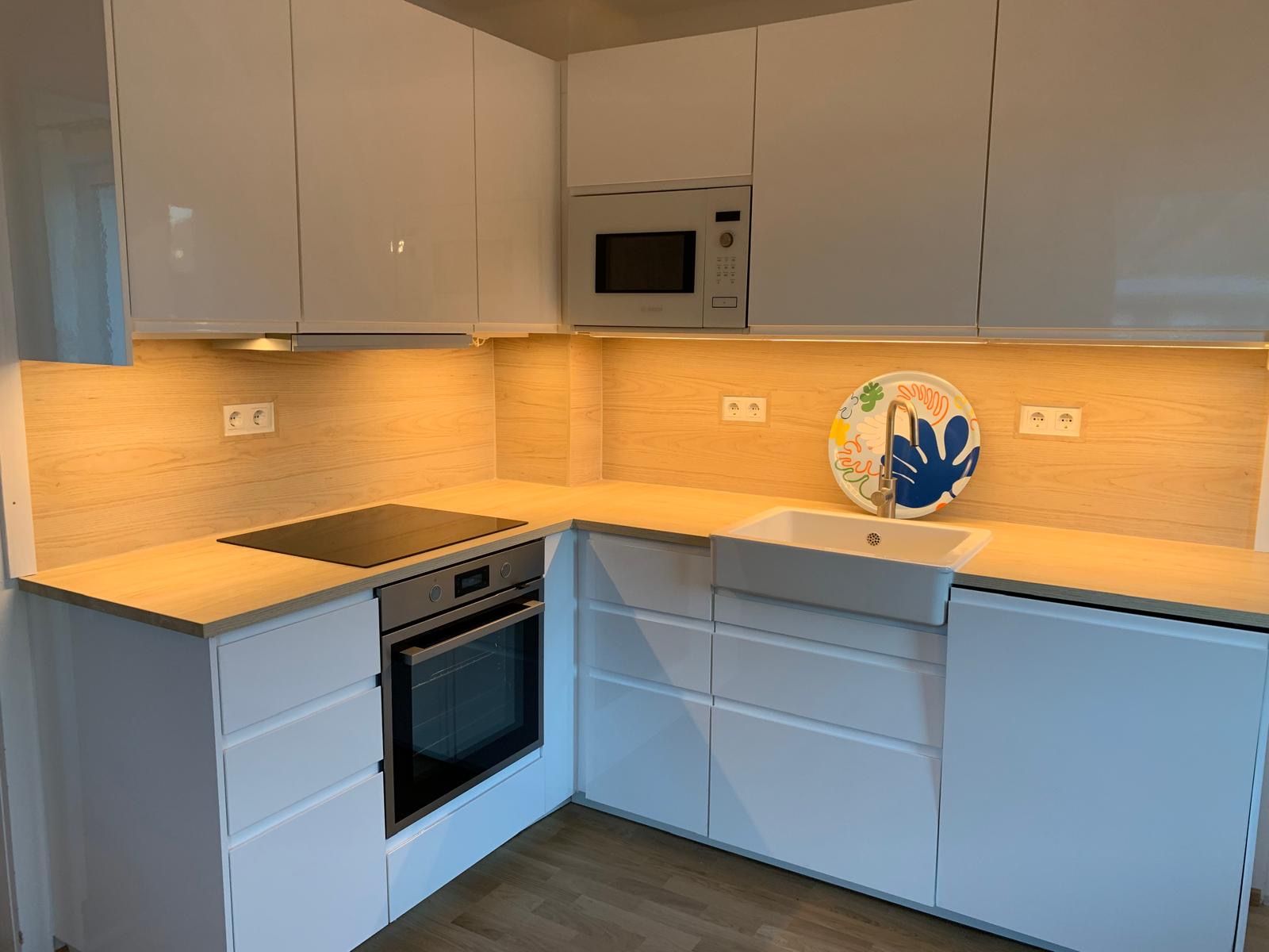 Modern kitchen with white cupboards, wooden worktop, built-in oven and sink.