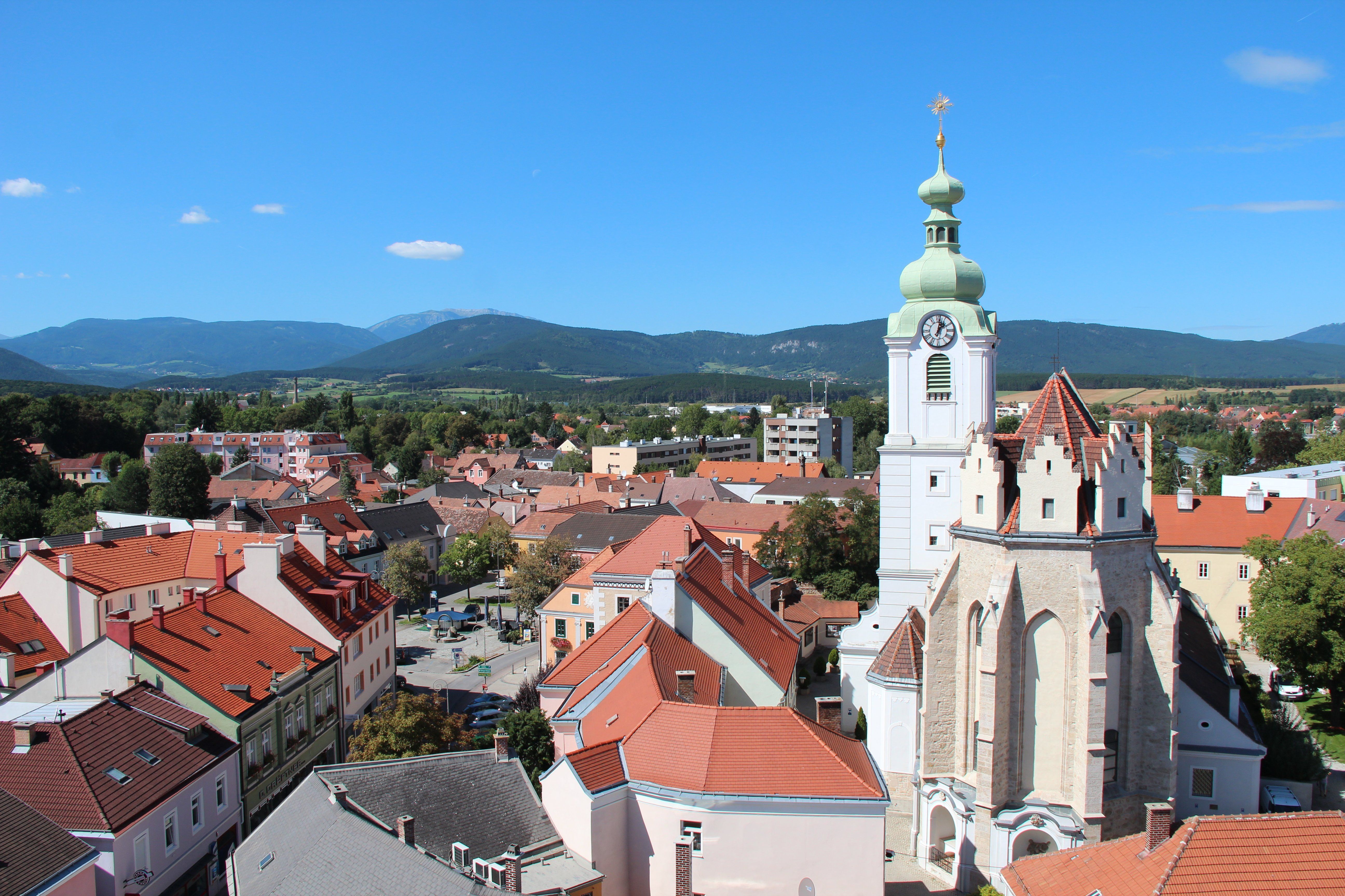Panoramic view of Neunkirchen with church and mountains in the background.