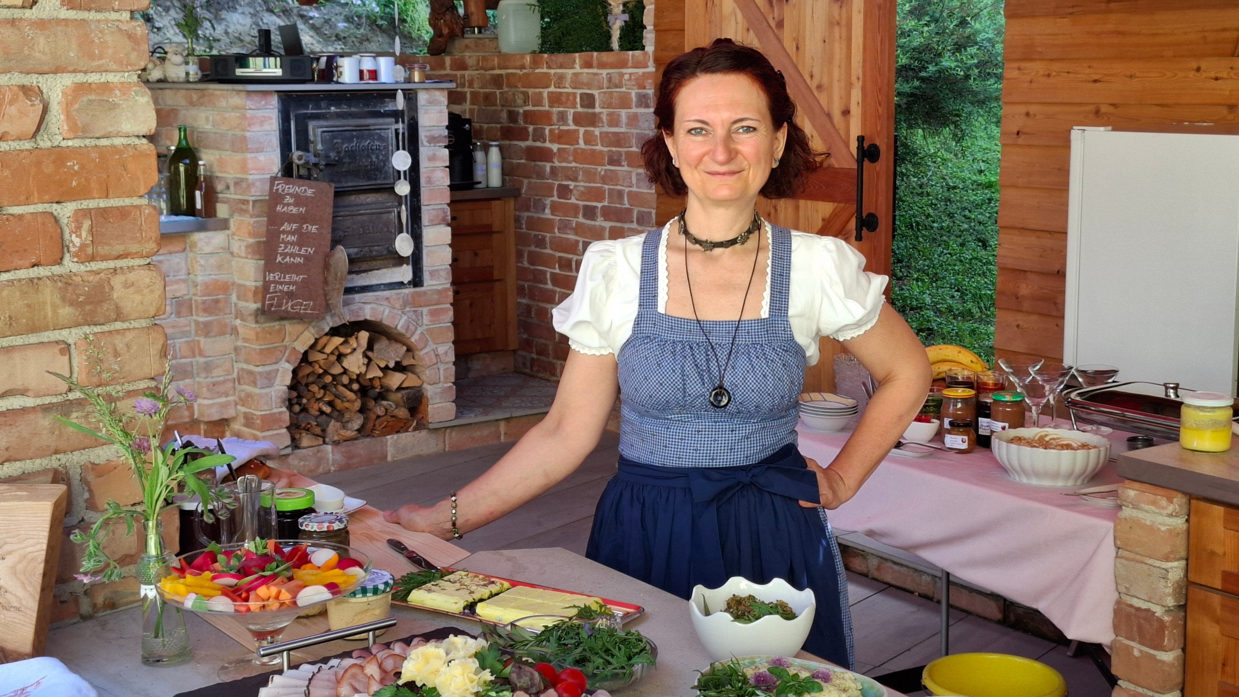 The chef in traditional dress in a rustic kitchen with dishes.