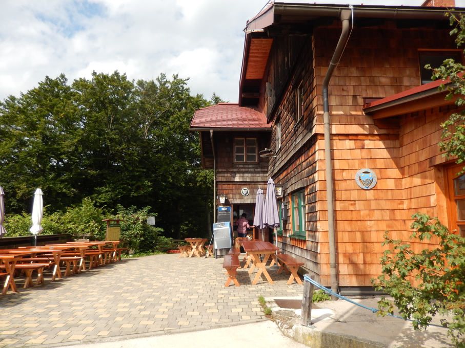 Wooden hut with terrace and outdoor benches.