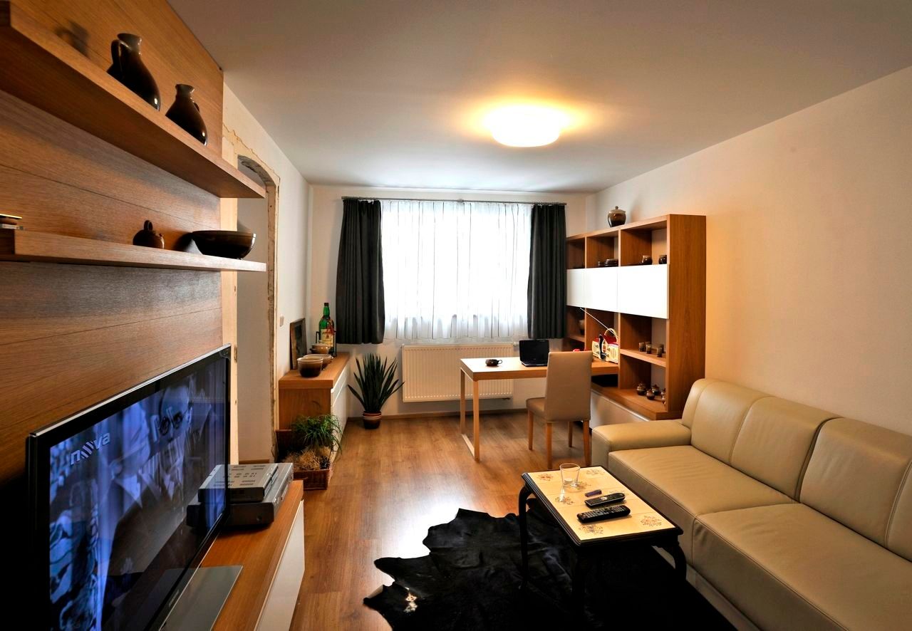 Modern furnished living room with sofa, TV, desk and shelves.