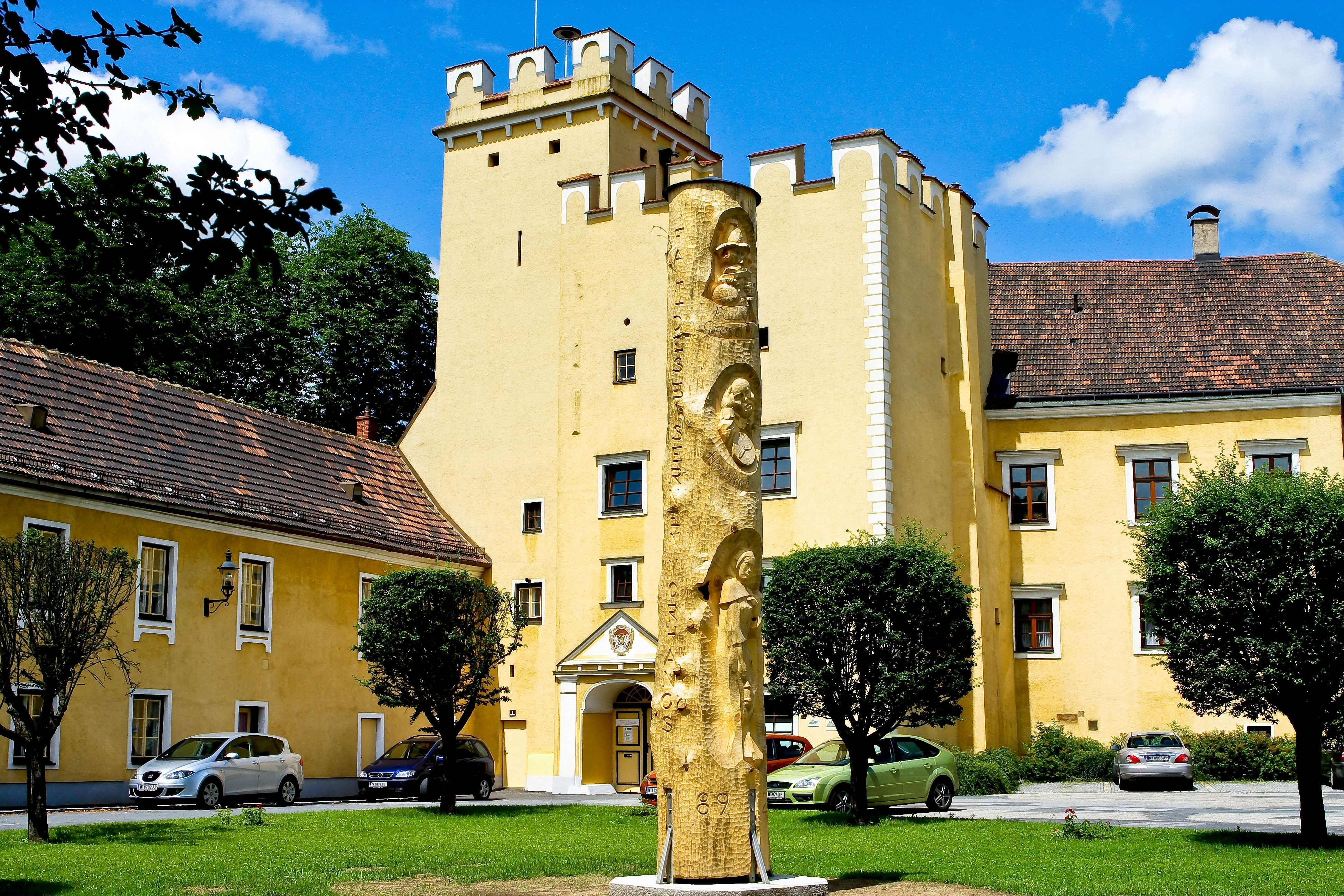 Yellow building with tower and golden sculpture in the foreground.