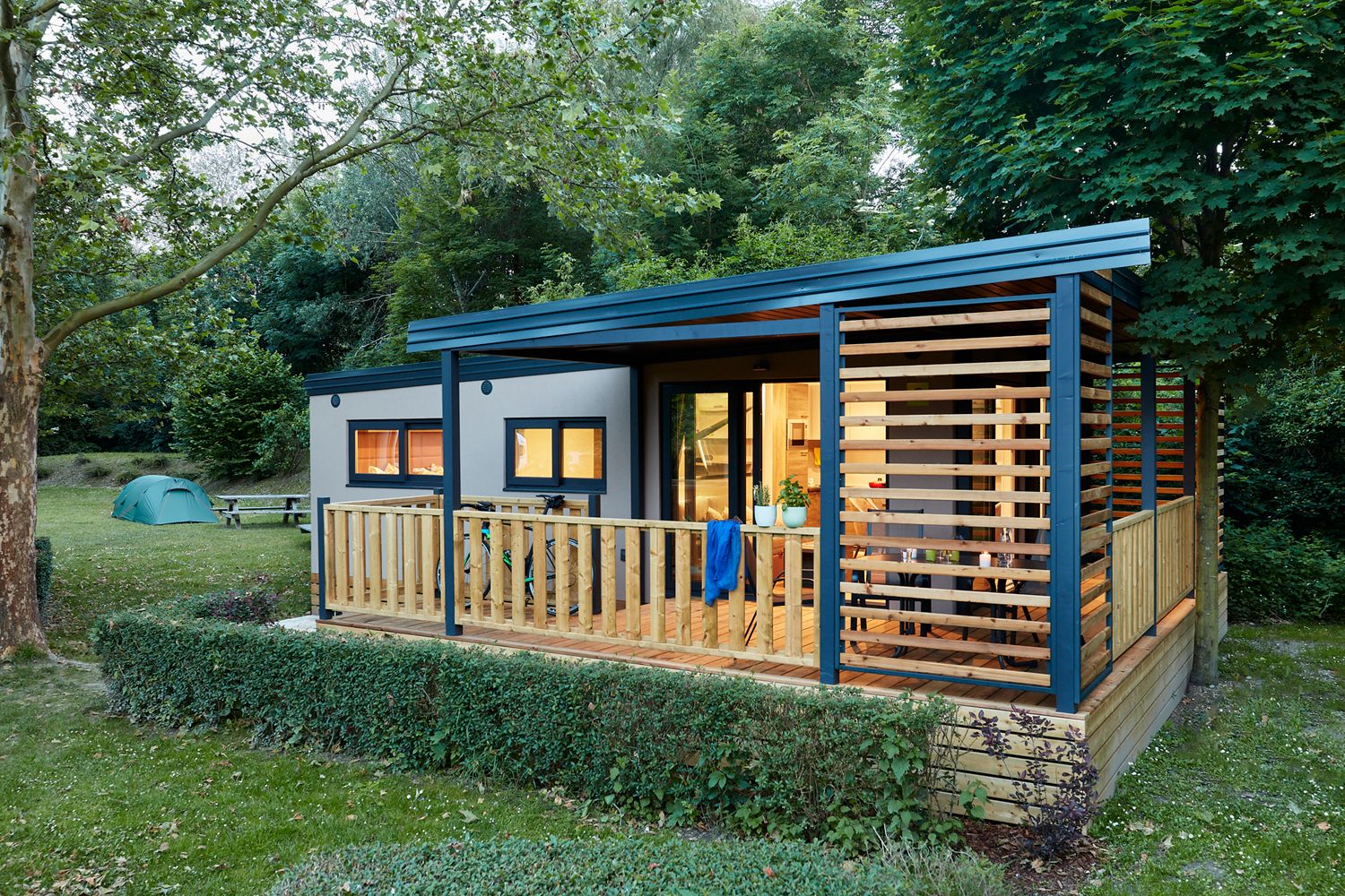 Mobile home from the outside with a view of the terrace and illuminated rooms 