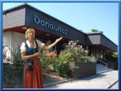 A woman in traditional dress stands in front of a building labeled 'Donauhof'.