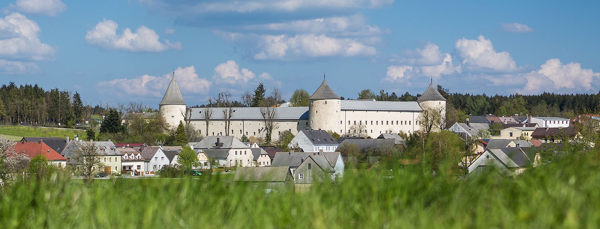 Ottenschlag Castle in a rural setting with blossoming trees and a clear blue sky.