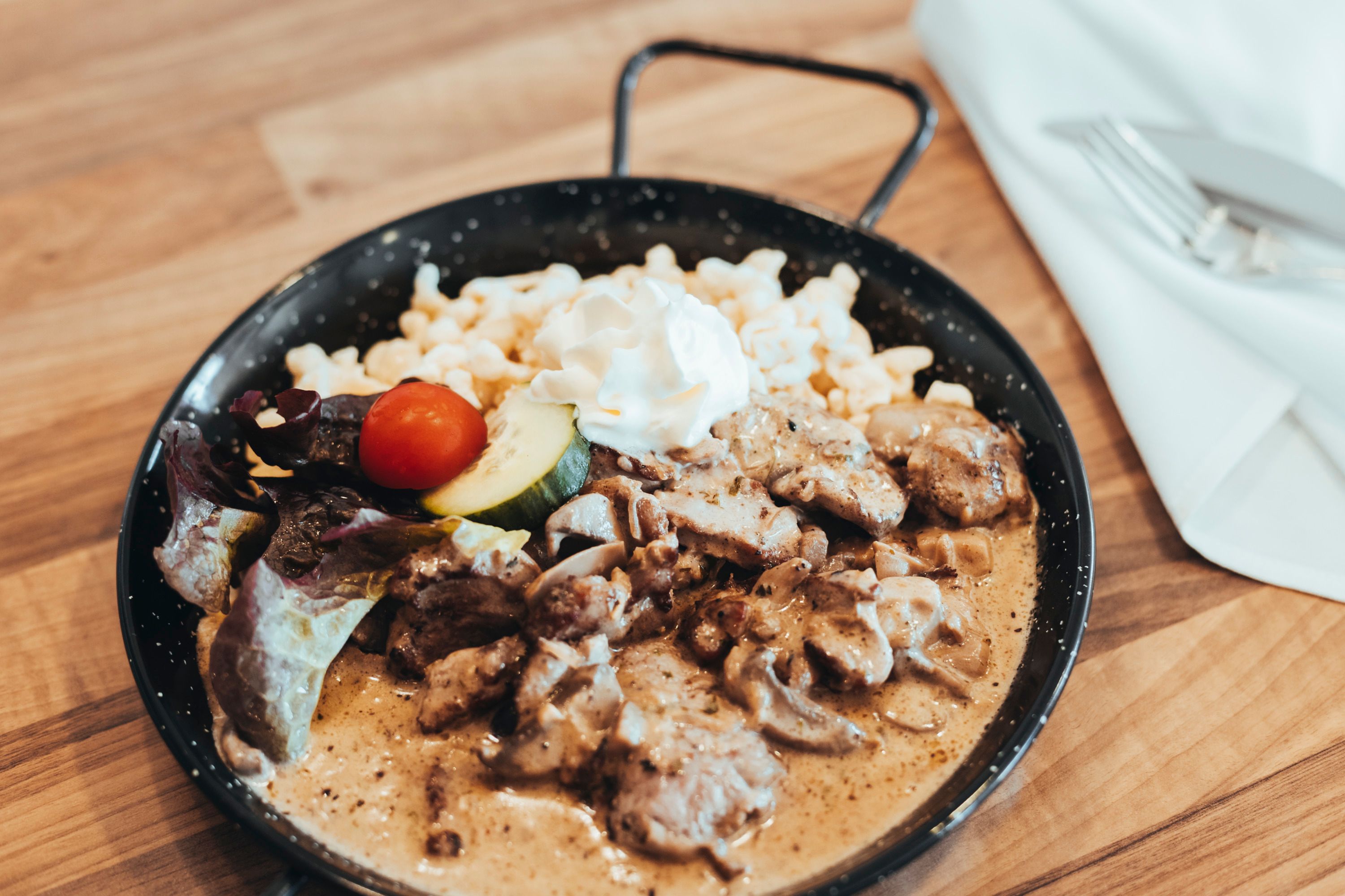 A dish in a pan with meat, spaetzle, cream and vegetables.