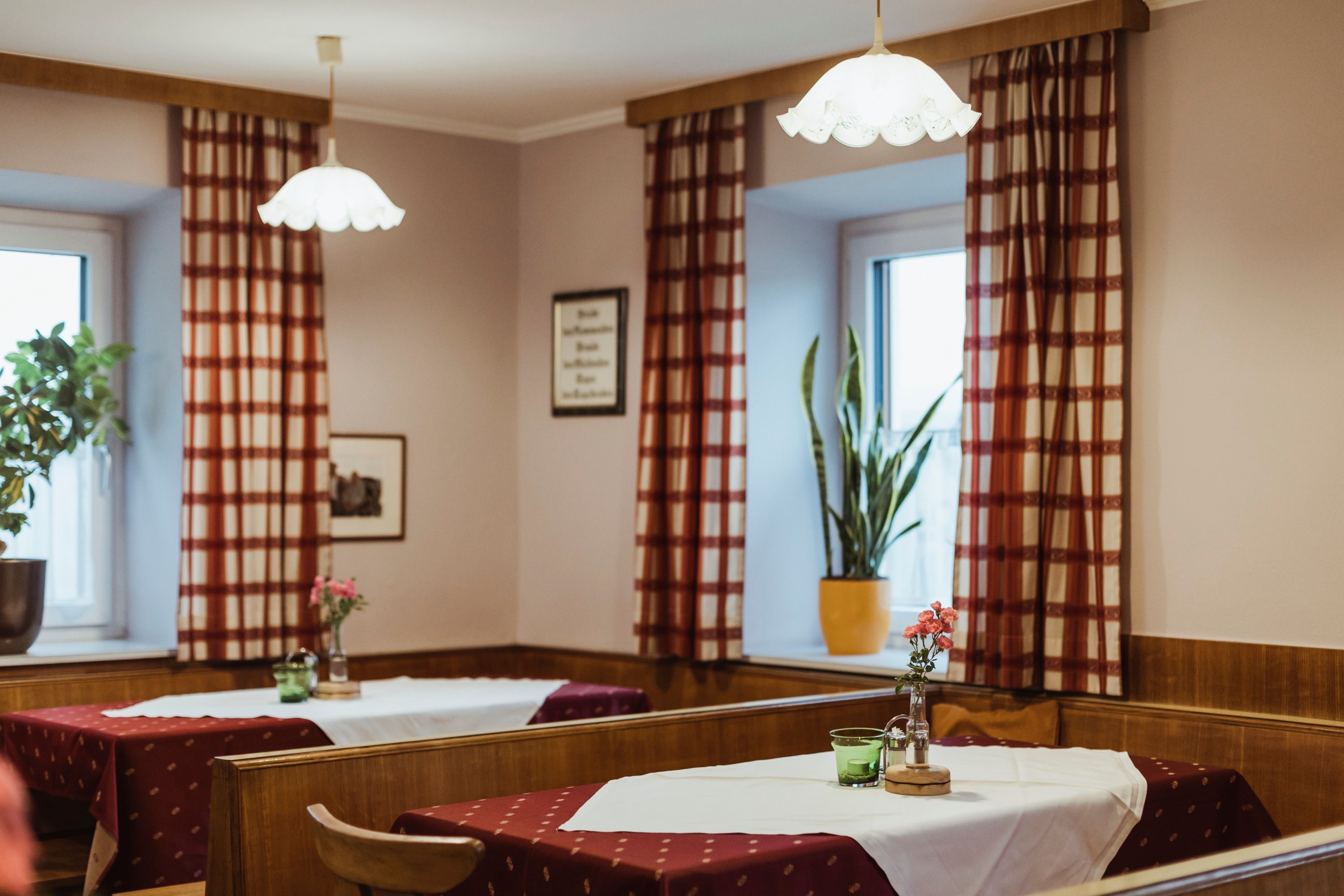 Cozy pub with wooden furniture, checkered curtains and decorated tables.