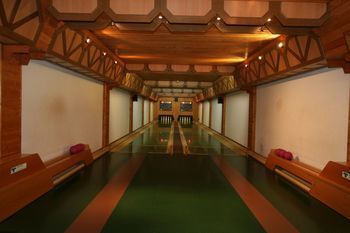 Interior view of a traditional bowling alley with wooden elements and two lanes.
