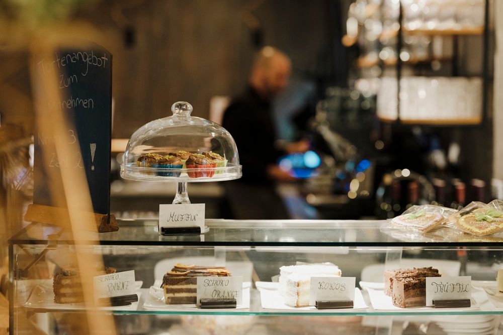 Confectionery with cakes and muffins in a glass display case, offer board in the background.