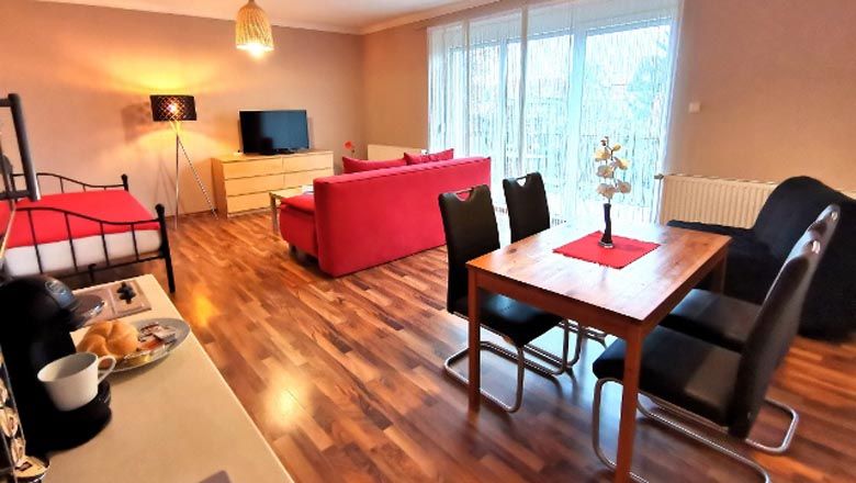 Modern living room with red sofa, dining table and flat screen TV.