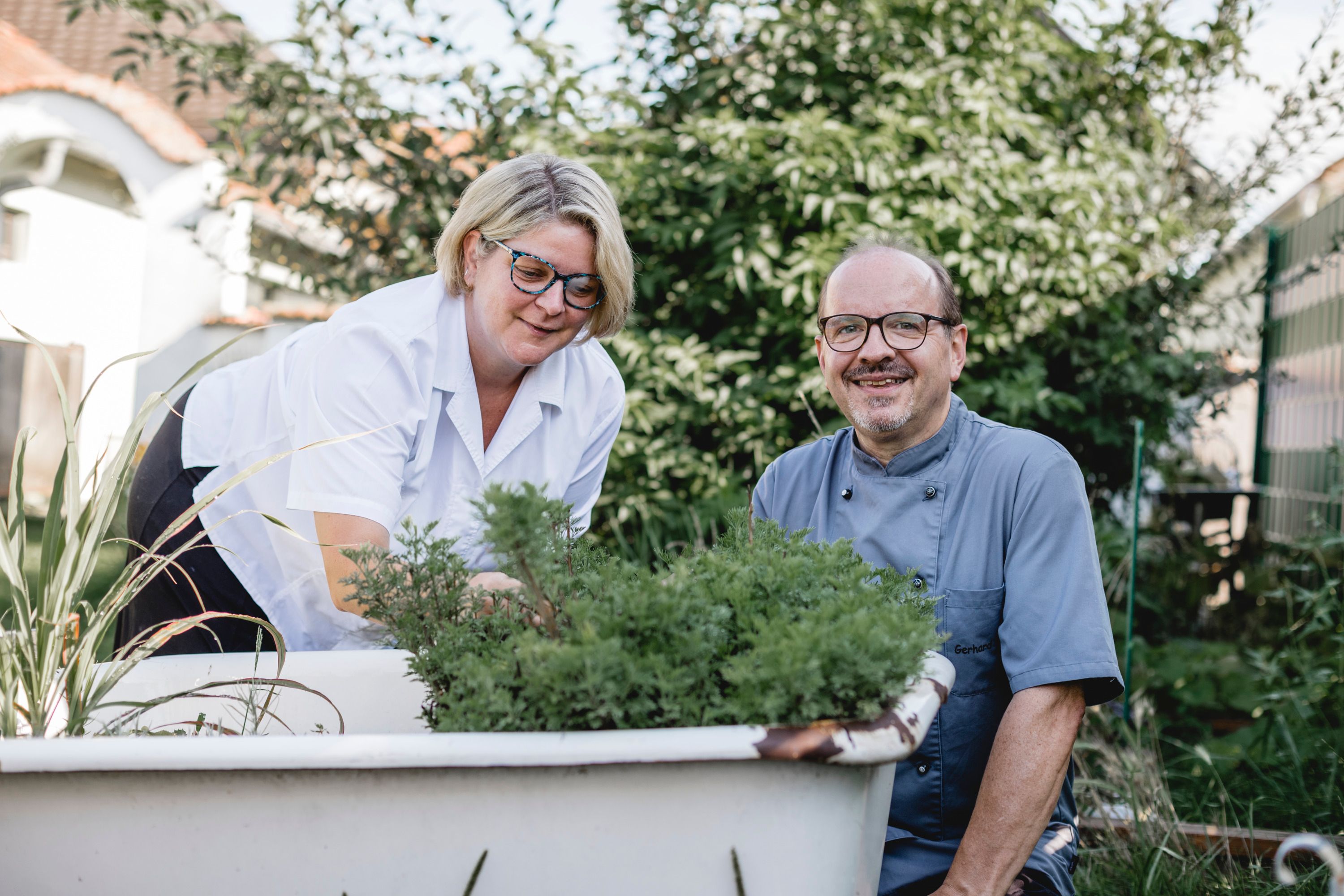 Two people gardening in an old outdoor bathtub.