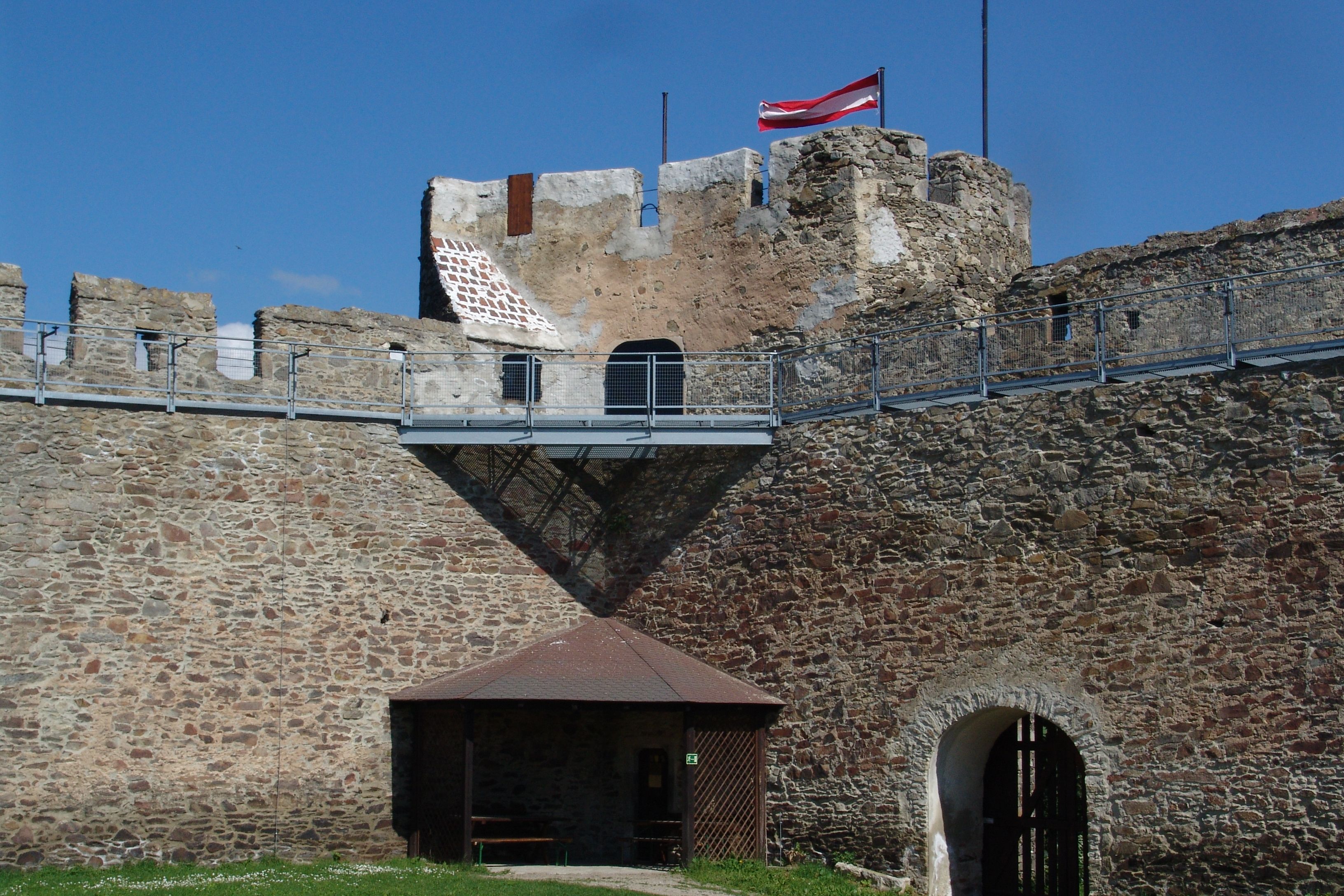 Old stone wall with Austrian flag on a tower.