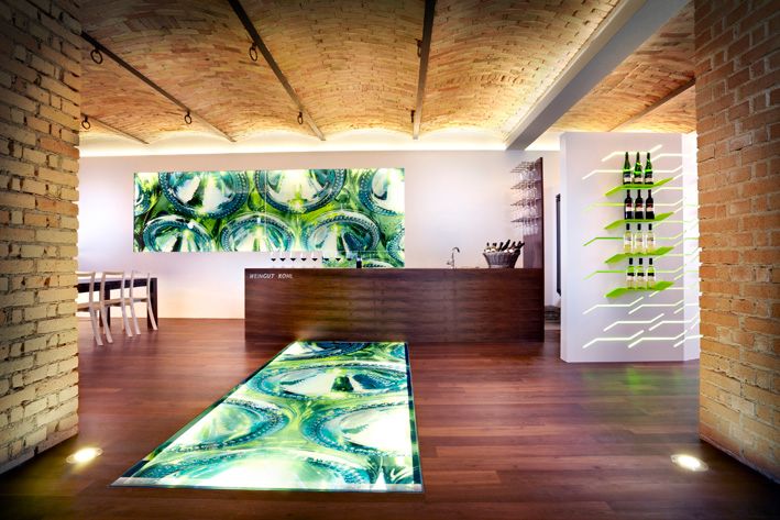 Modern winery interior with illuminated floor and wine bottles on the wall.