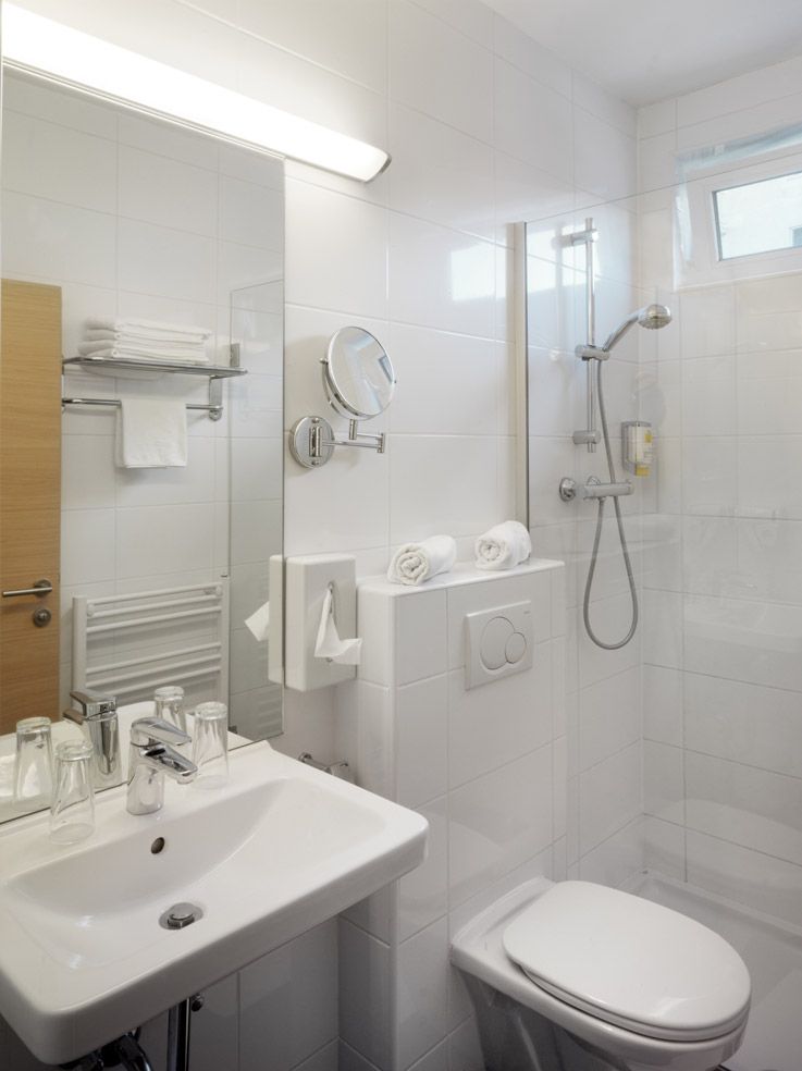 Modern hotel bathroom with shower, washbasin and toilet.