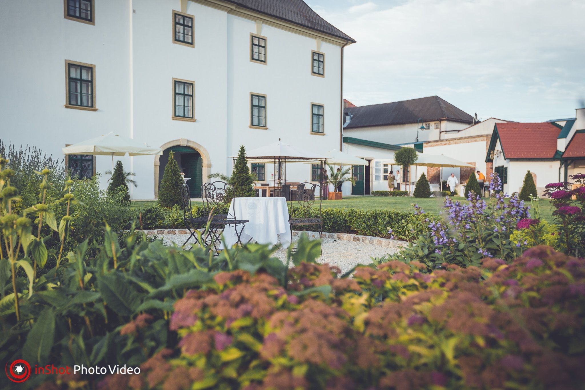 Garden view of Raggendorf Castle with flowers, tables and chairs in the foreground.