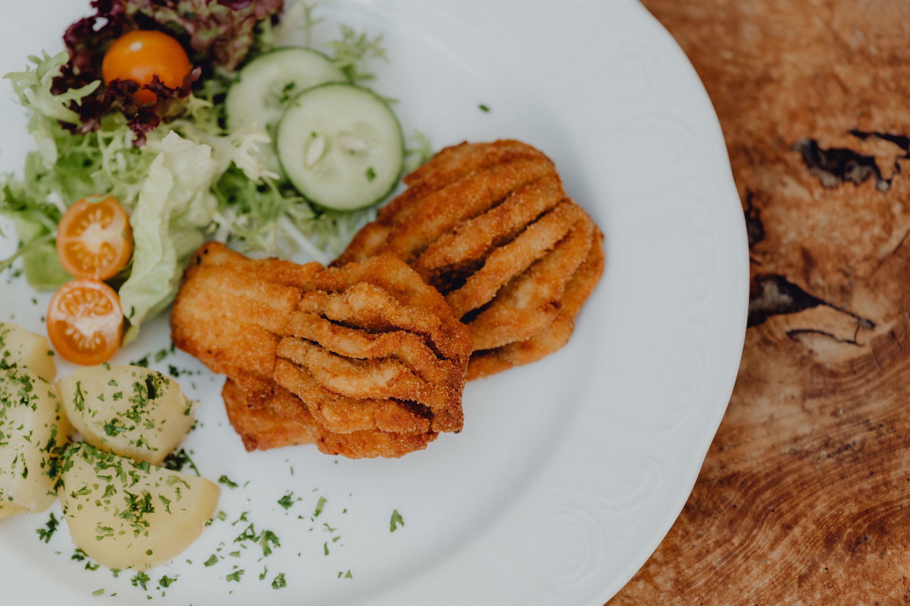 A plate of breaded fish, potatoes and salad.