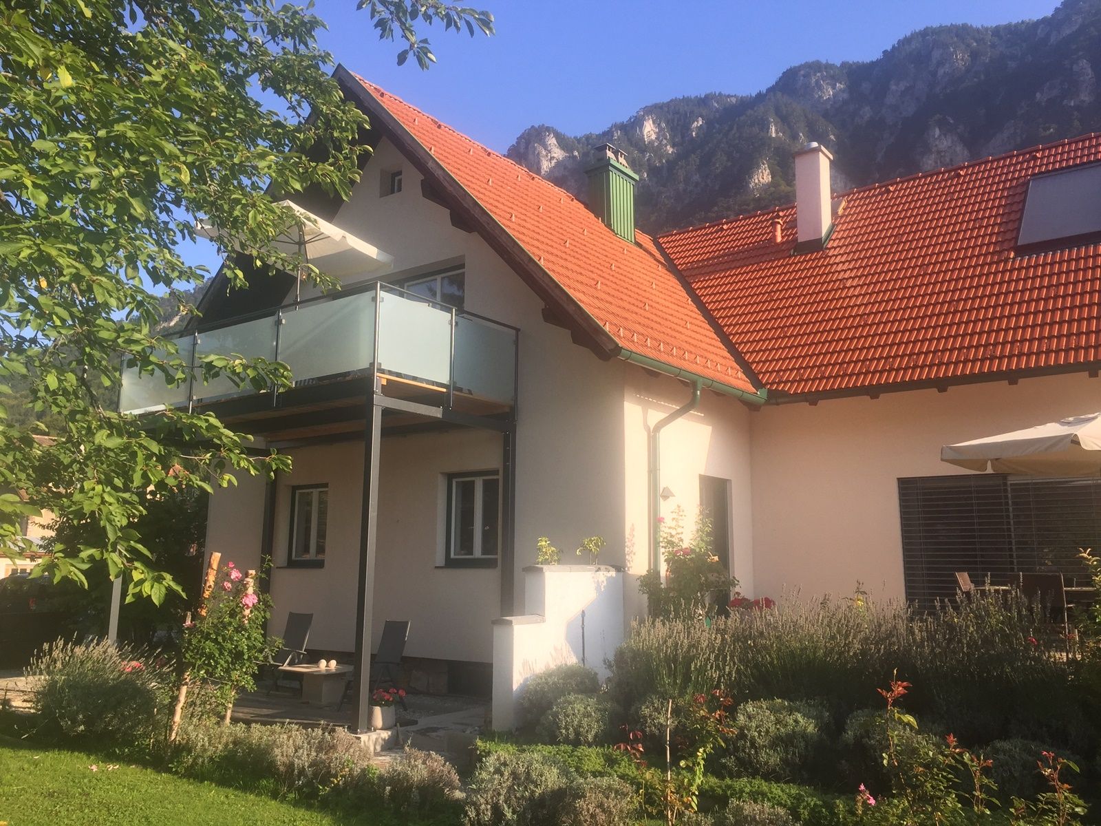 Vacation home with balcony and garden against a mountain backdrop.