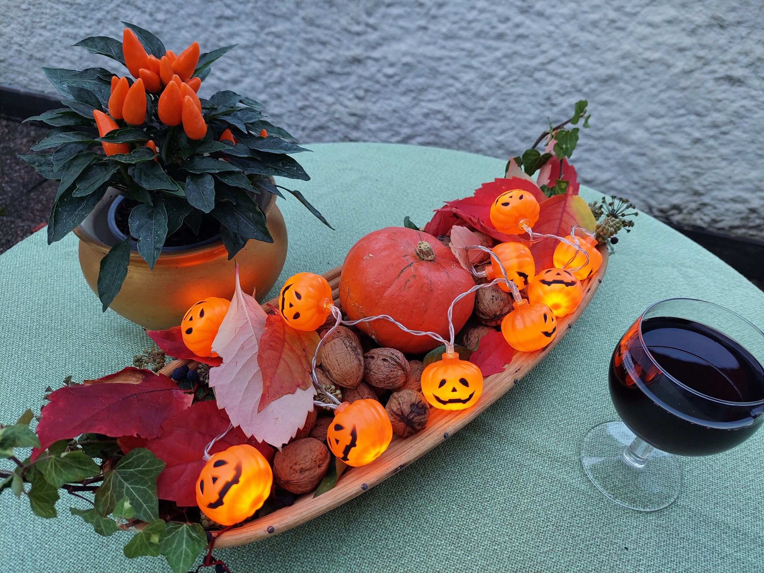 Autumnal table decoration with pumpkin, fairy lights and drink.