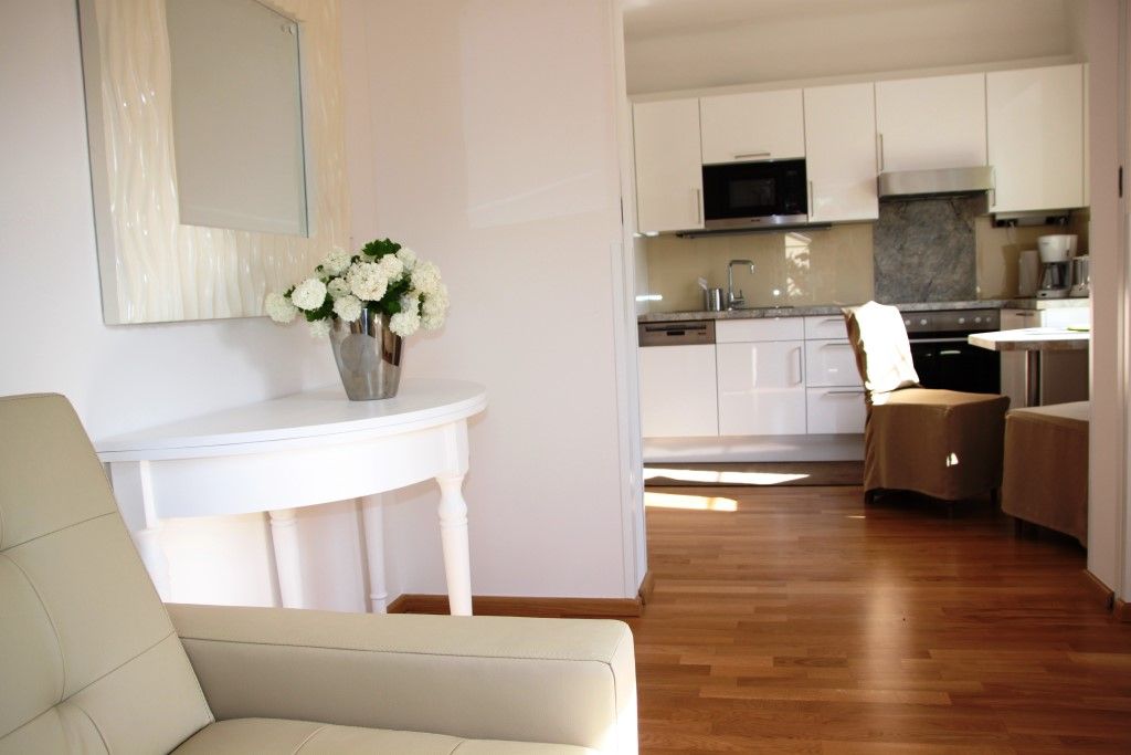 Interior view of a modern living area with kitchen and flowers on a table.