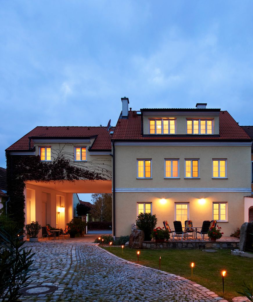 Illuminated building with paved path and garden furniture in the foreground.