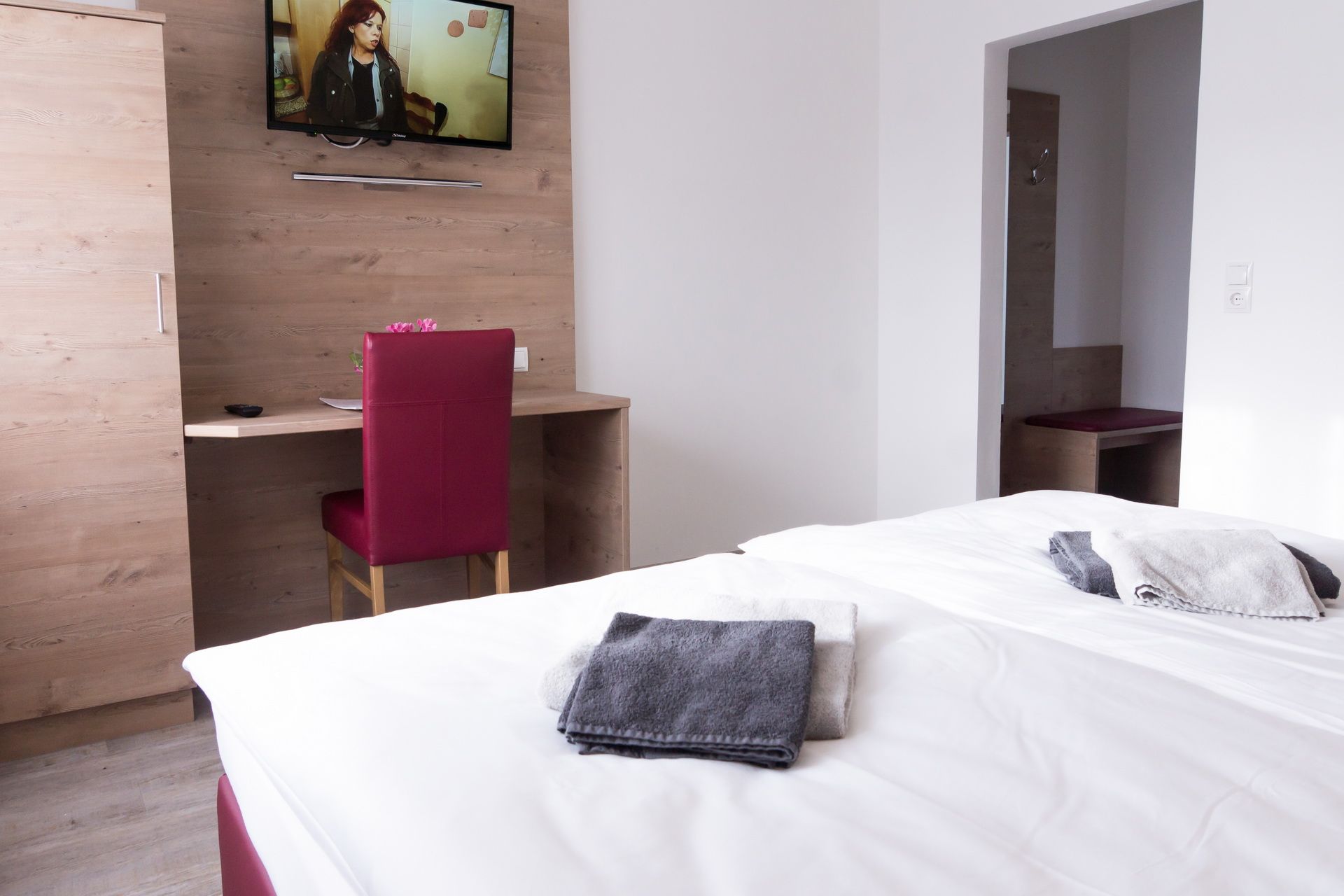 Double room with bed, desk, chair and TV on the wall.