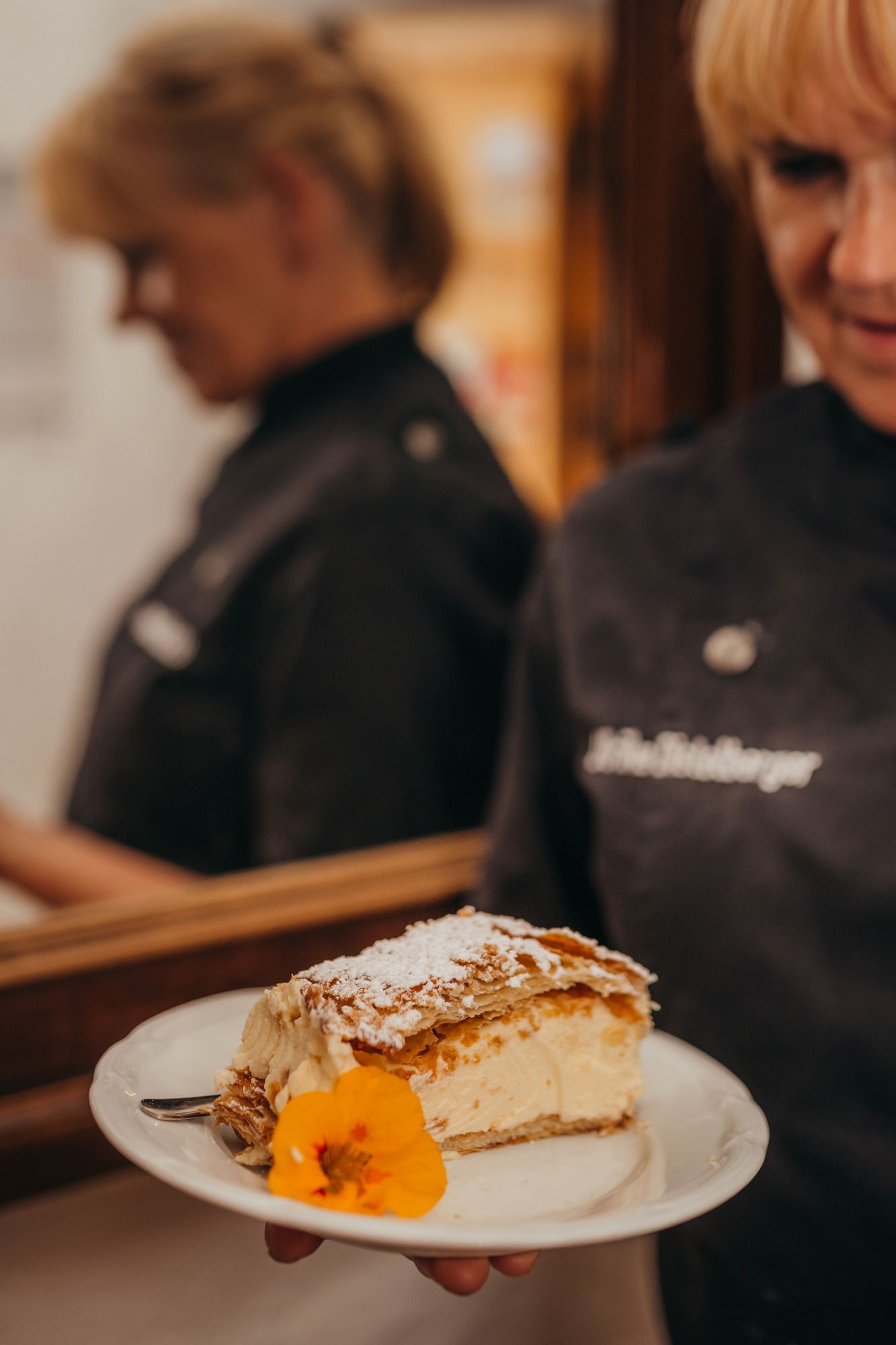One person is holding a plate with a piece of cake decorated with a flower.