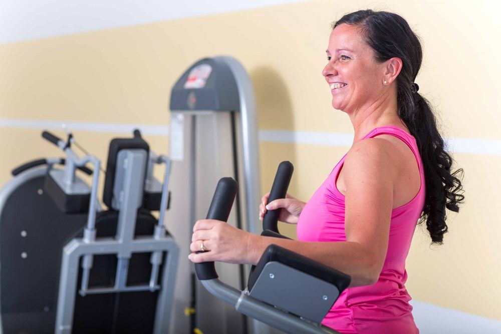 Woman exercising on a cross trainer in the gym.