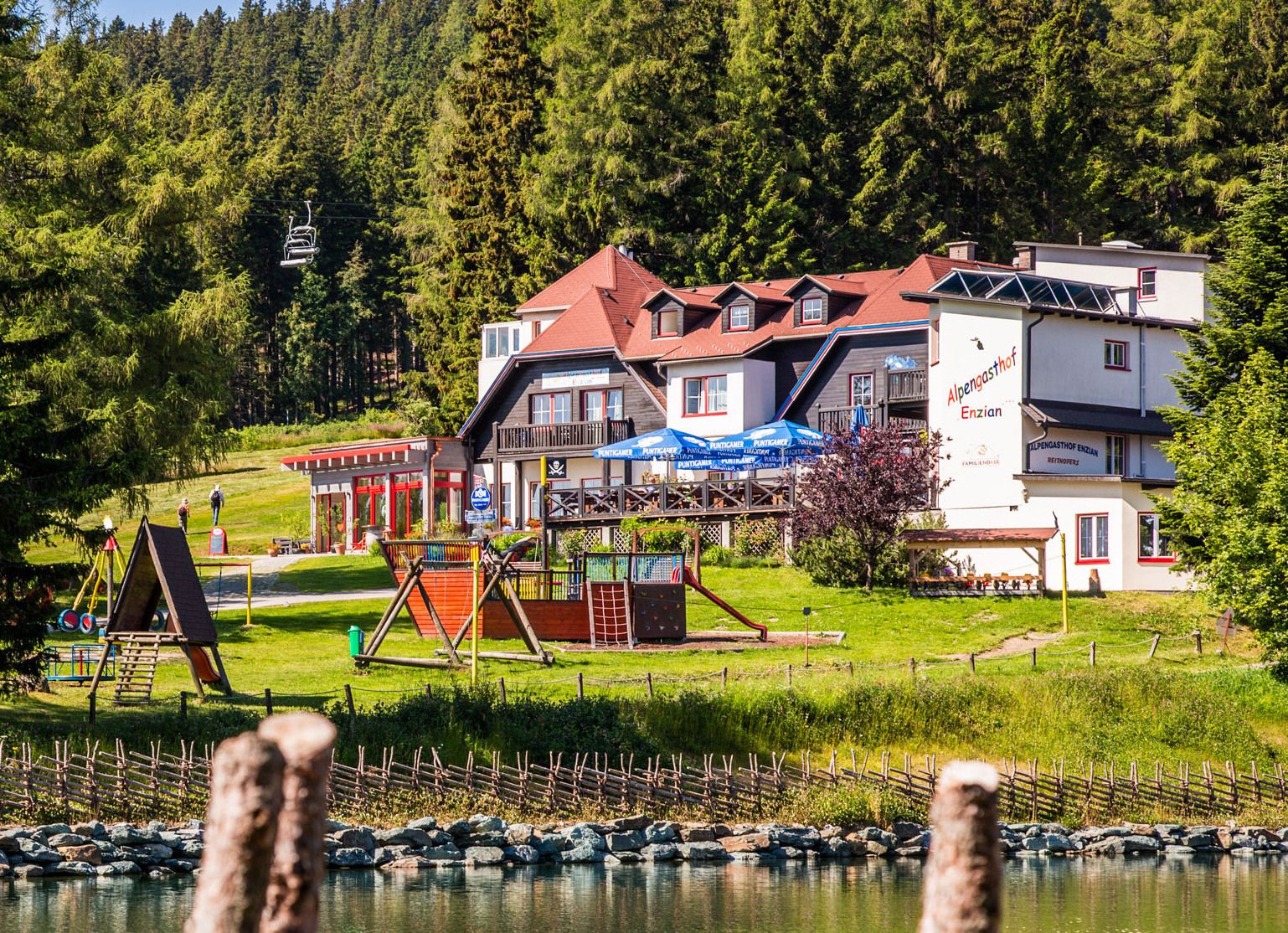 Alpengasthof Enzian with playground and forest in the background.