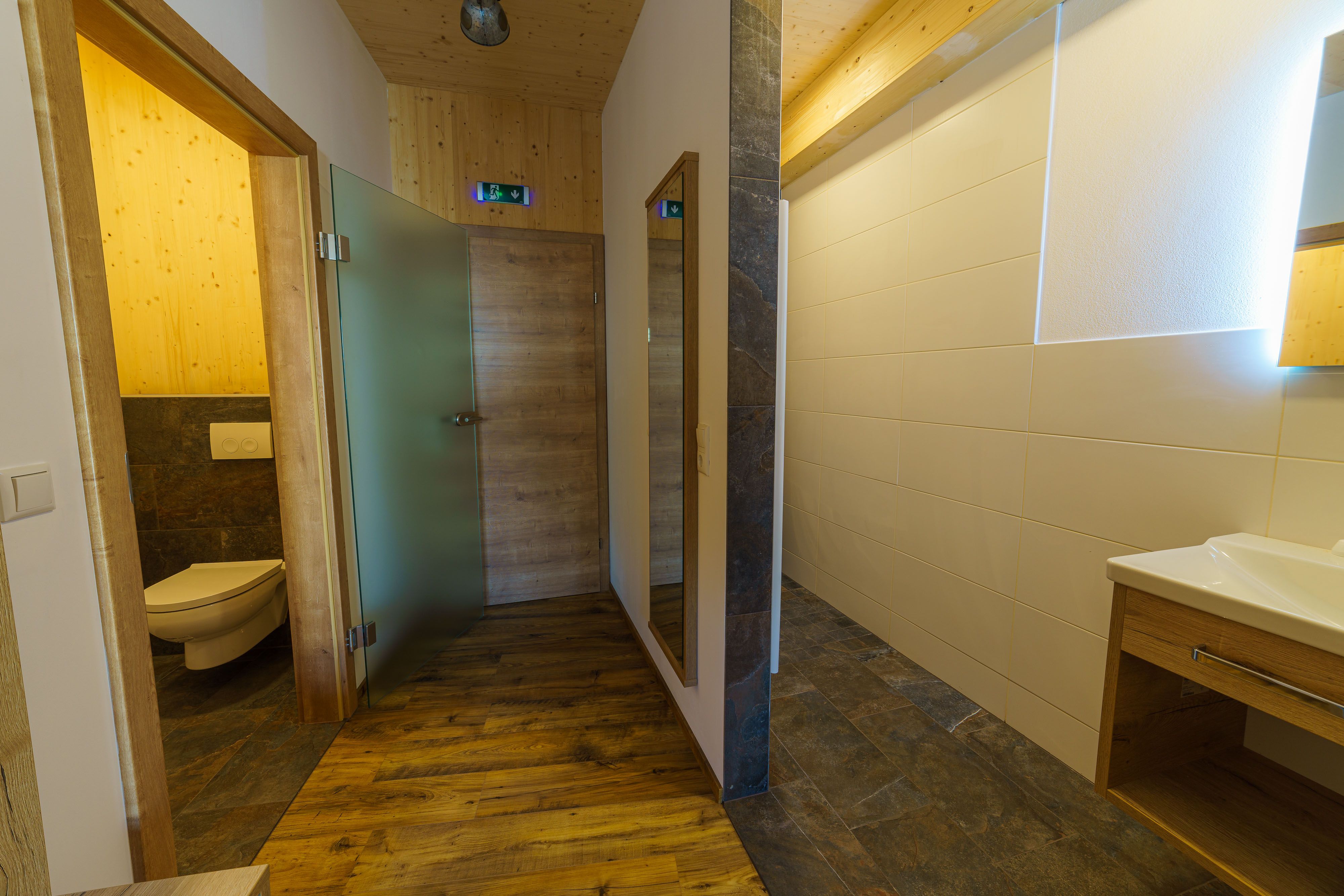Modern bathroom with wooden elements and glass details.