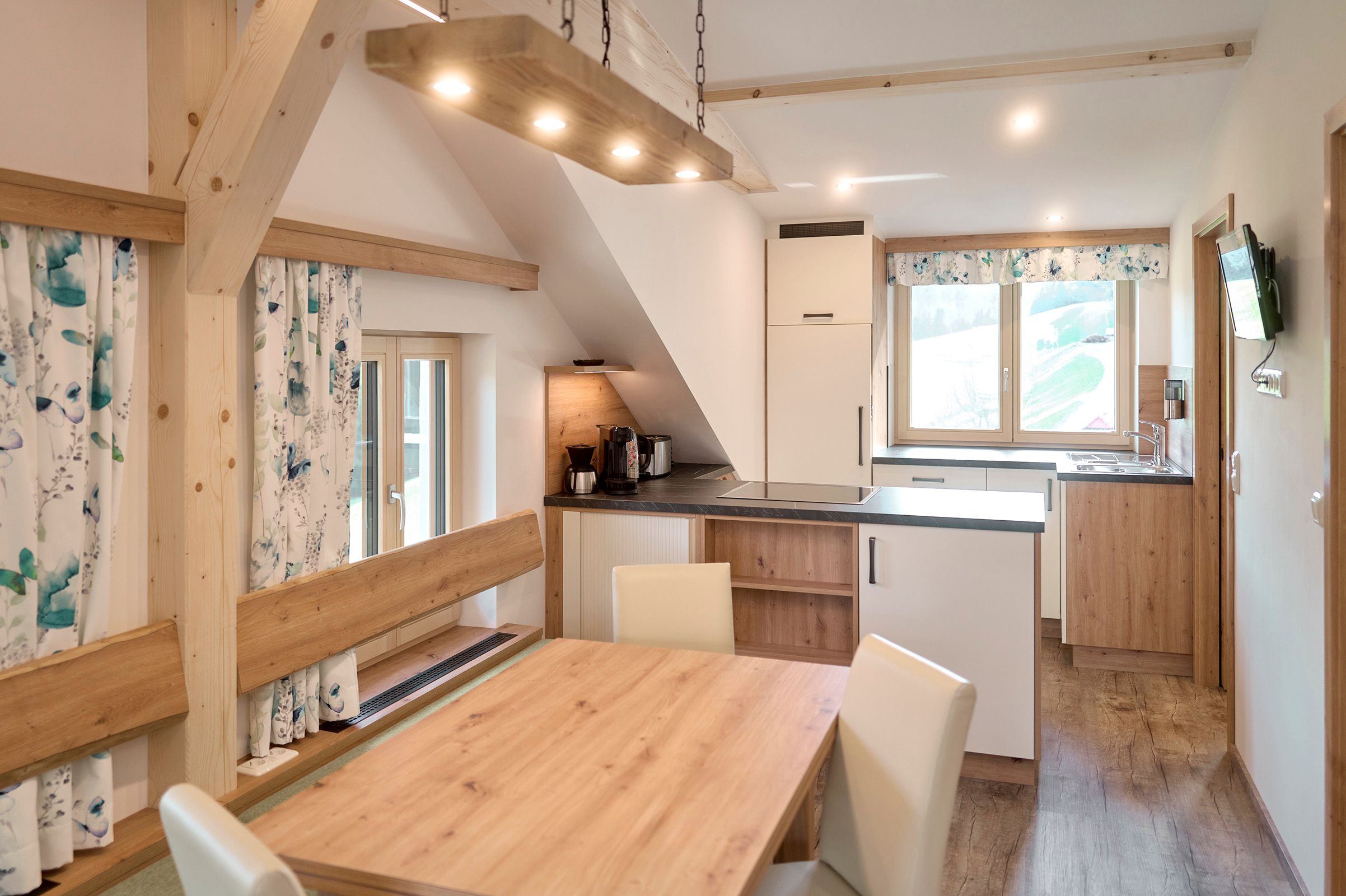 Modern eat-in kitchen with wooden furniture and large windows.