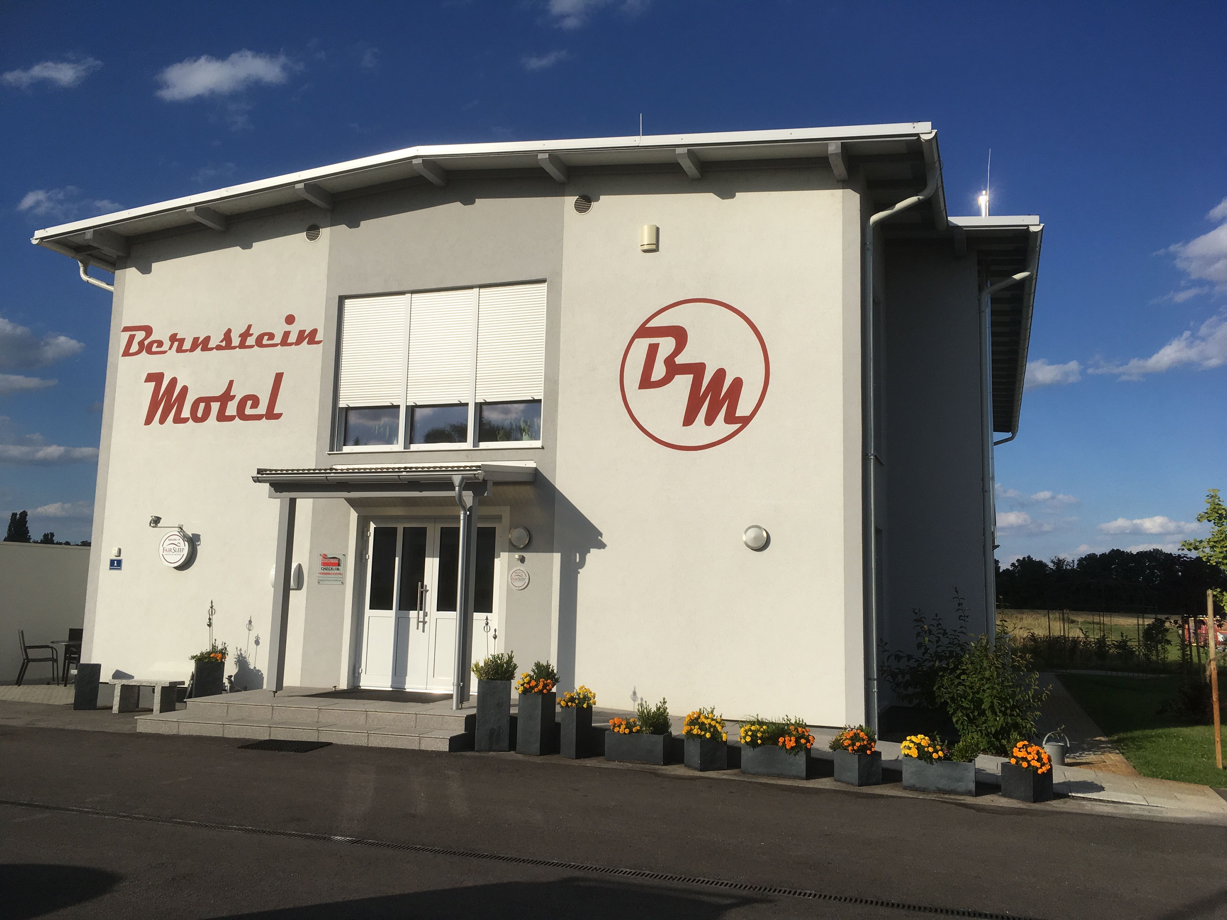 Exterior view of the Bernstein Motel with flowers and blue sky.