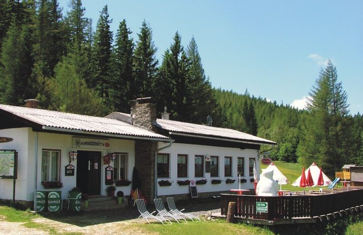 Almrausch hut in a forest landscape with sunshades and deckchairs.