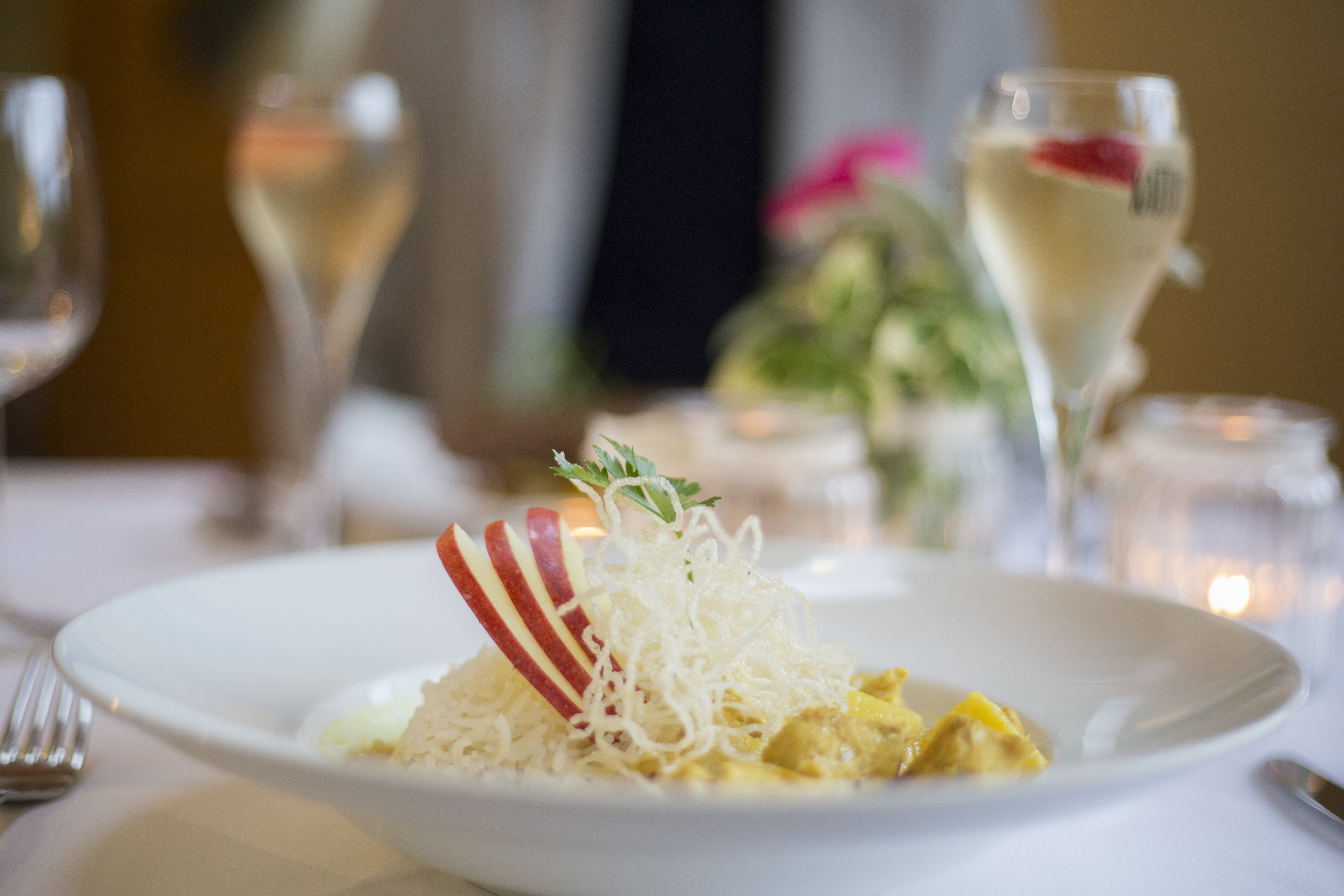 A plate with rice, apple slices and a garnish on a laid table.