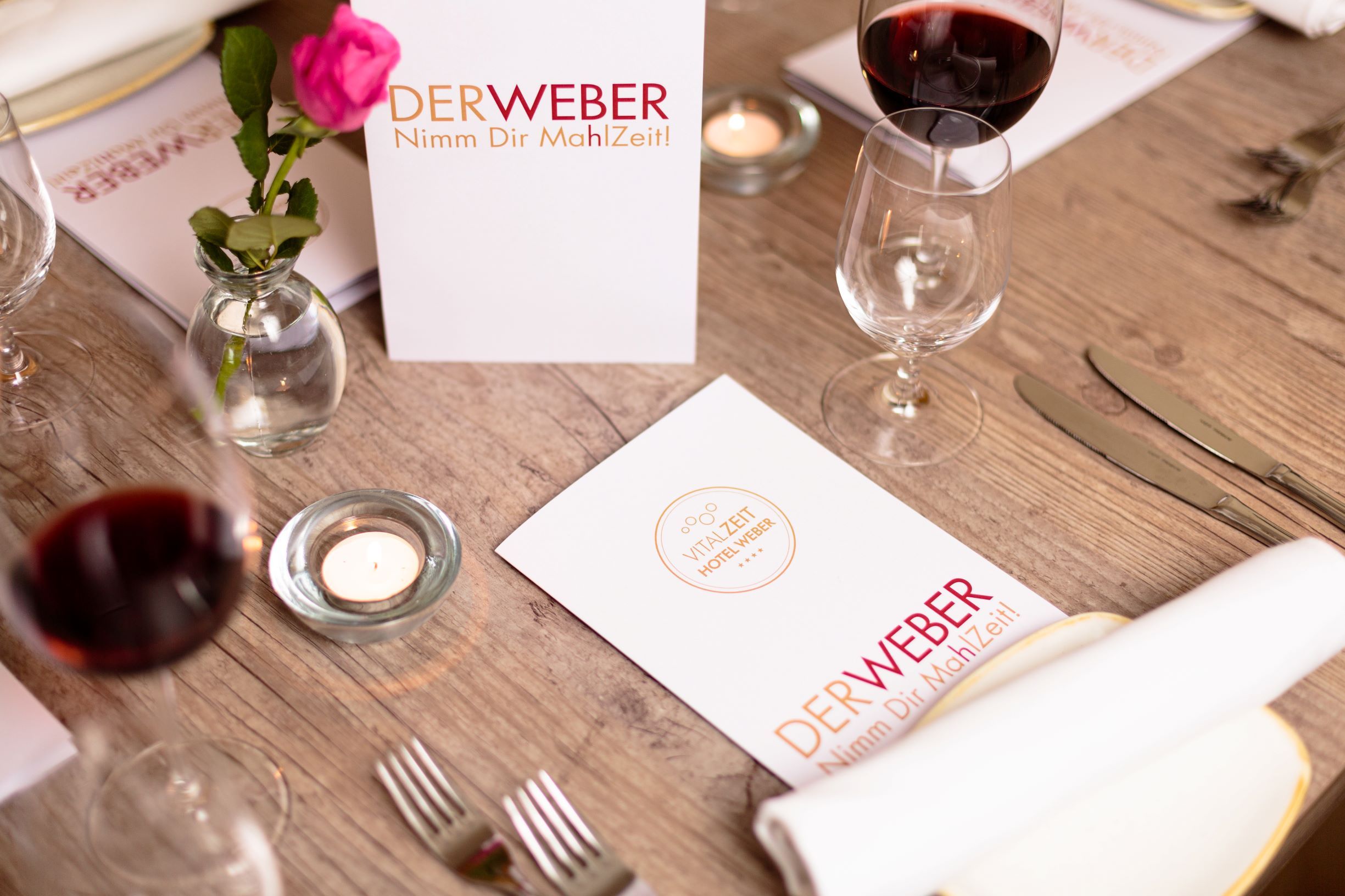 Table setting at Restaurant Der Weber with menu cards, wine glasses and a rose.