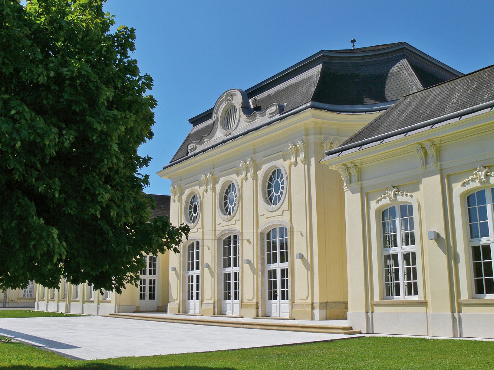 Historic building with a yellow façade and large windows in the sunshine.