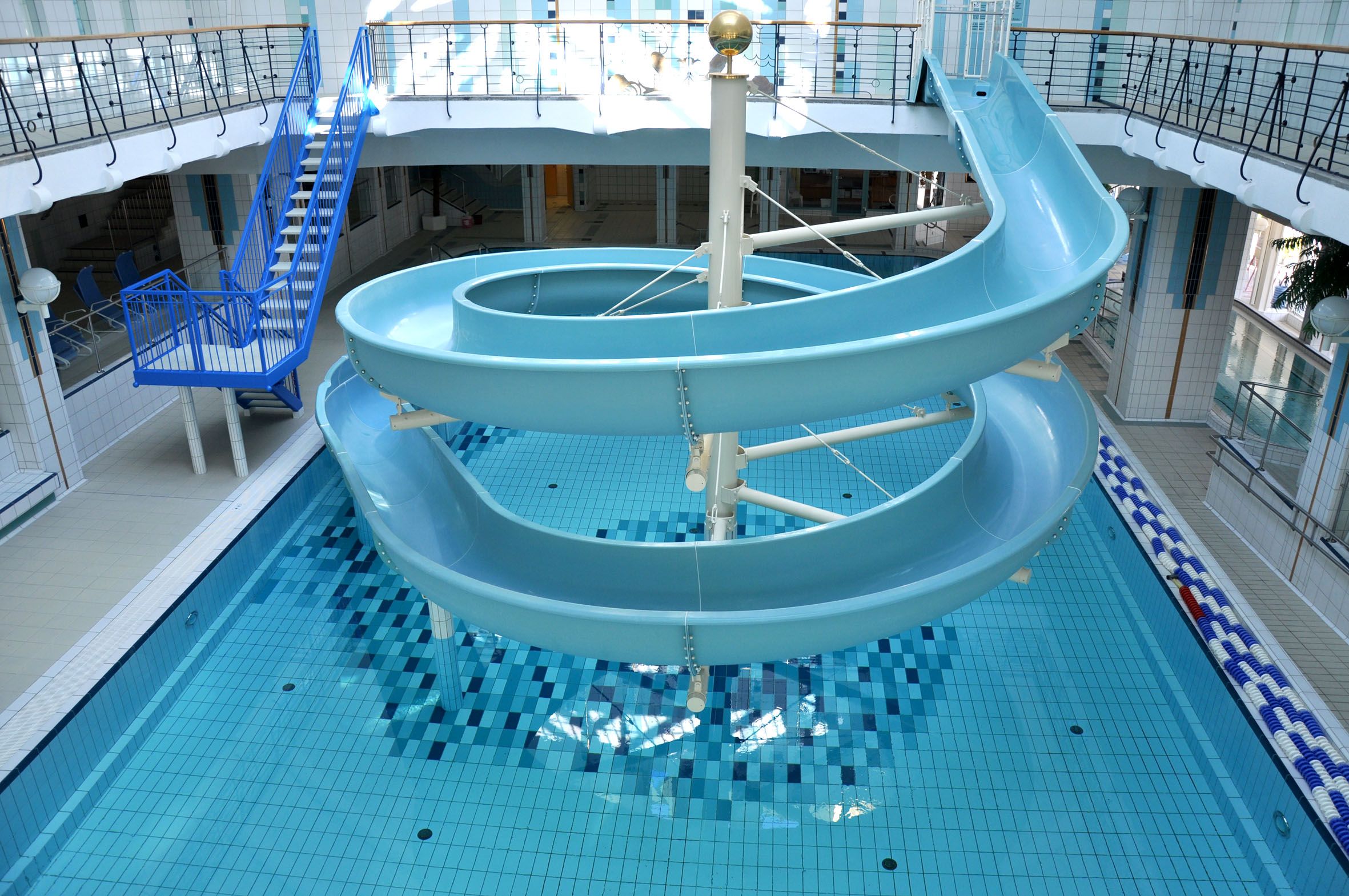 Interior view of an indoor pool with blue water slide and swimming pool.