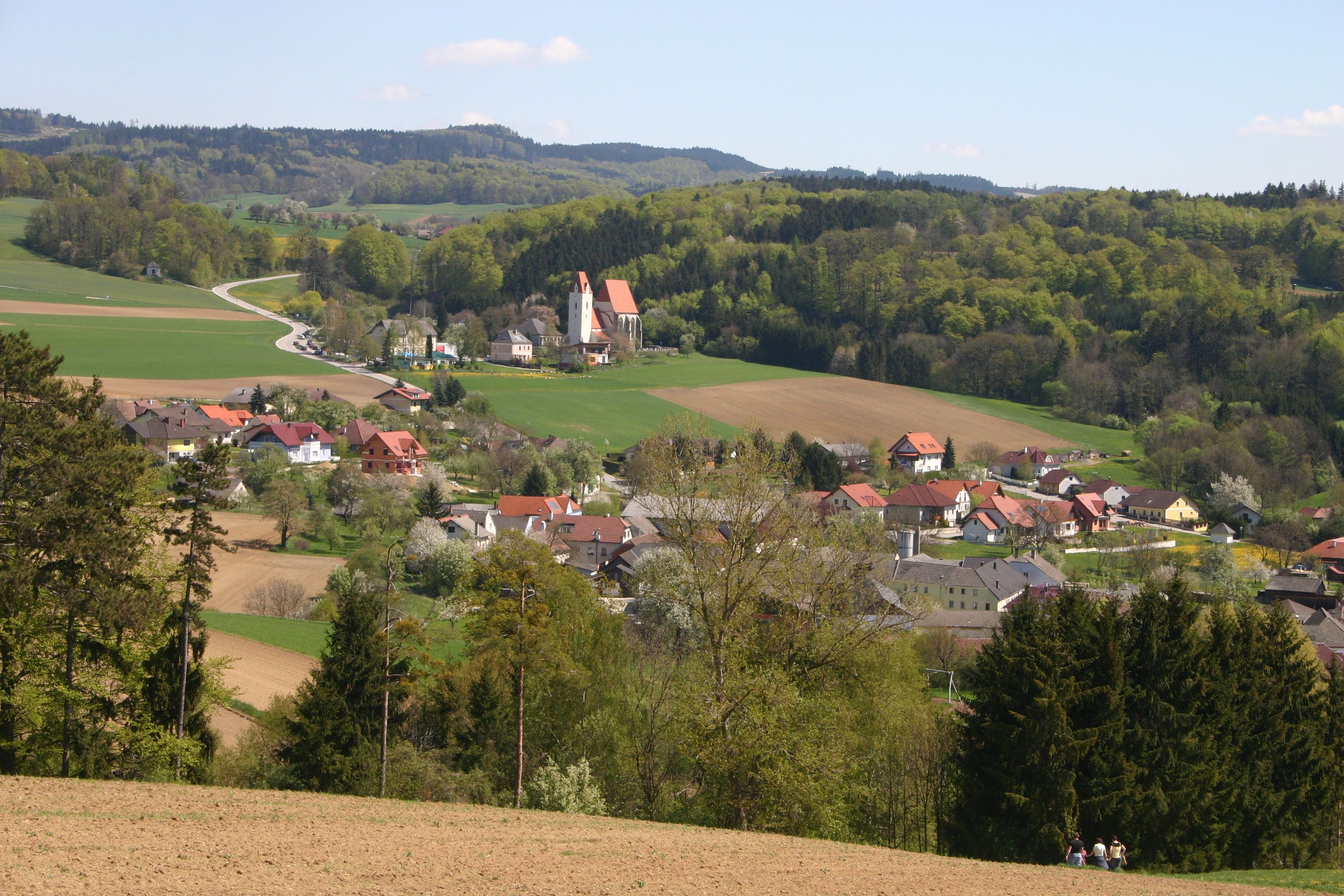 Landscape with village, church and hills in the background.