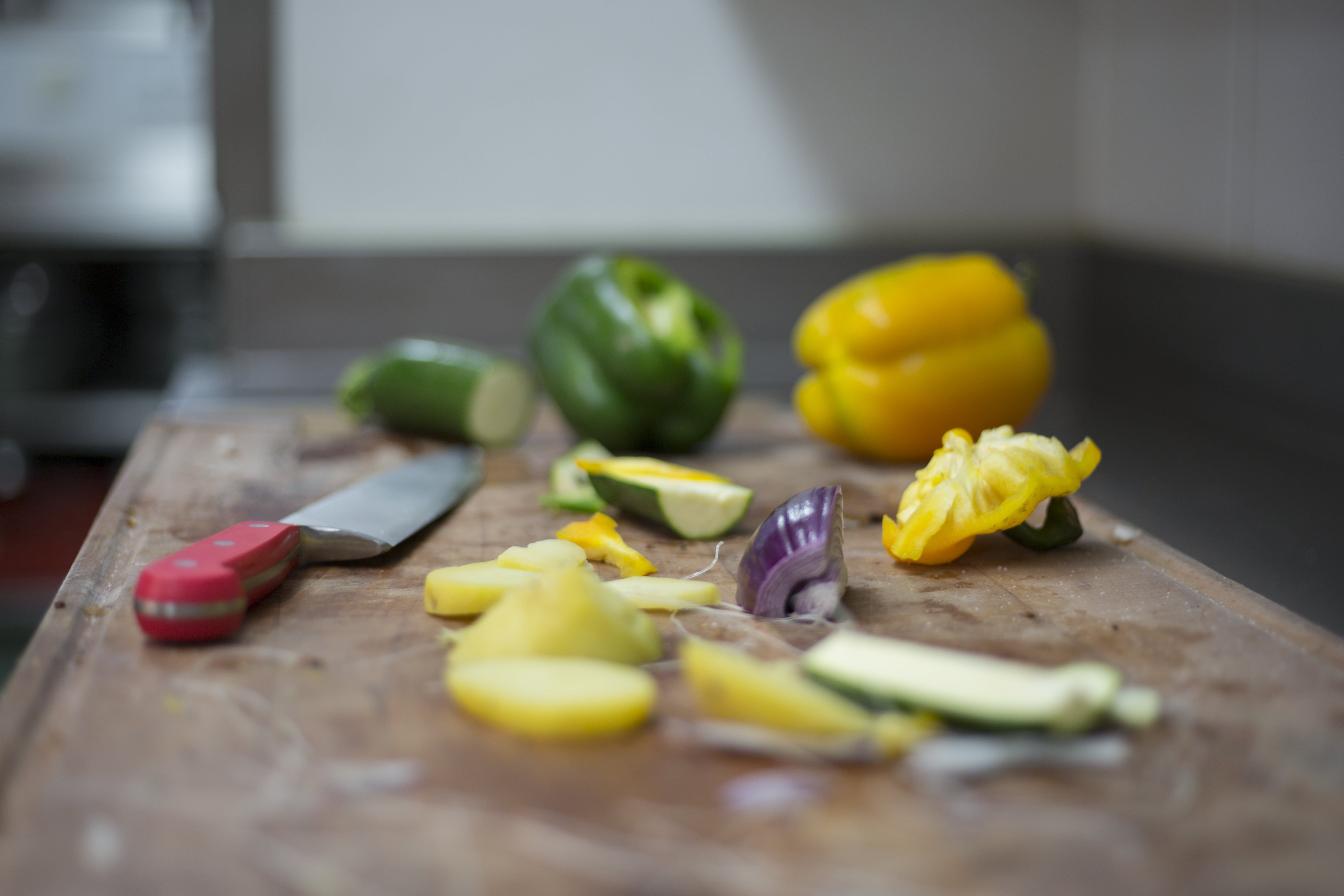 Vegetables and knives on a chopping board in a kitchen.