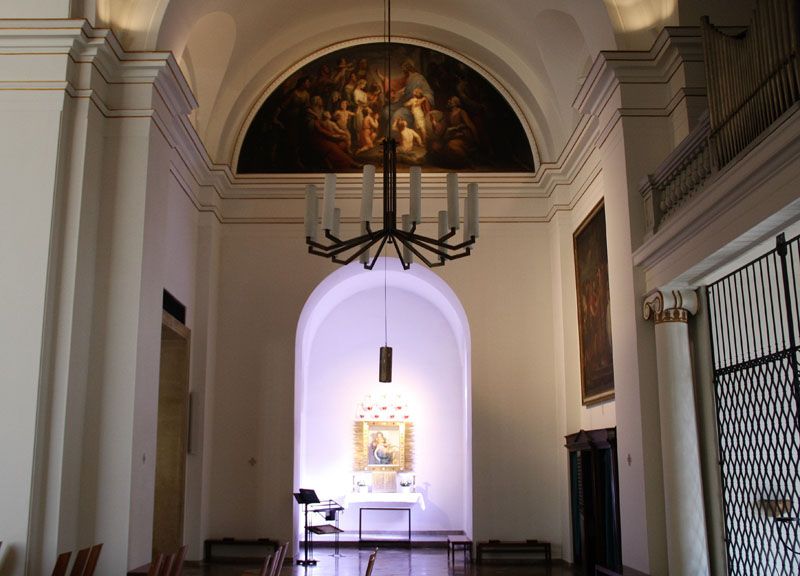Interior view of a church with altar and painting on the wall.