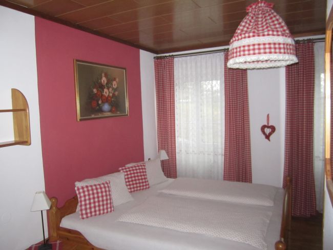 Bedroom with red and white checked curtains and bed linen.